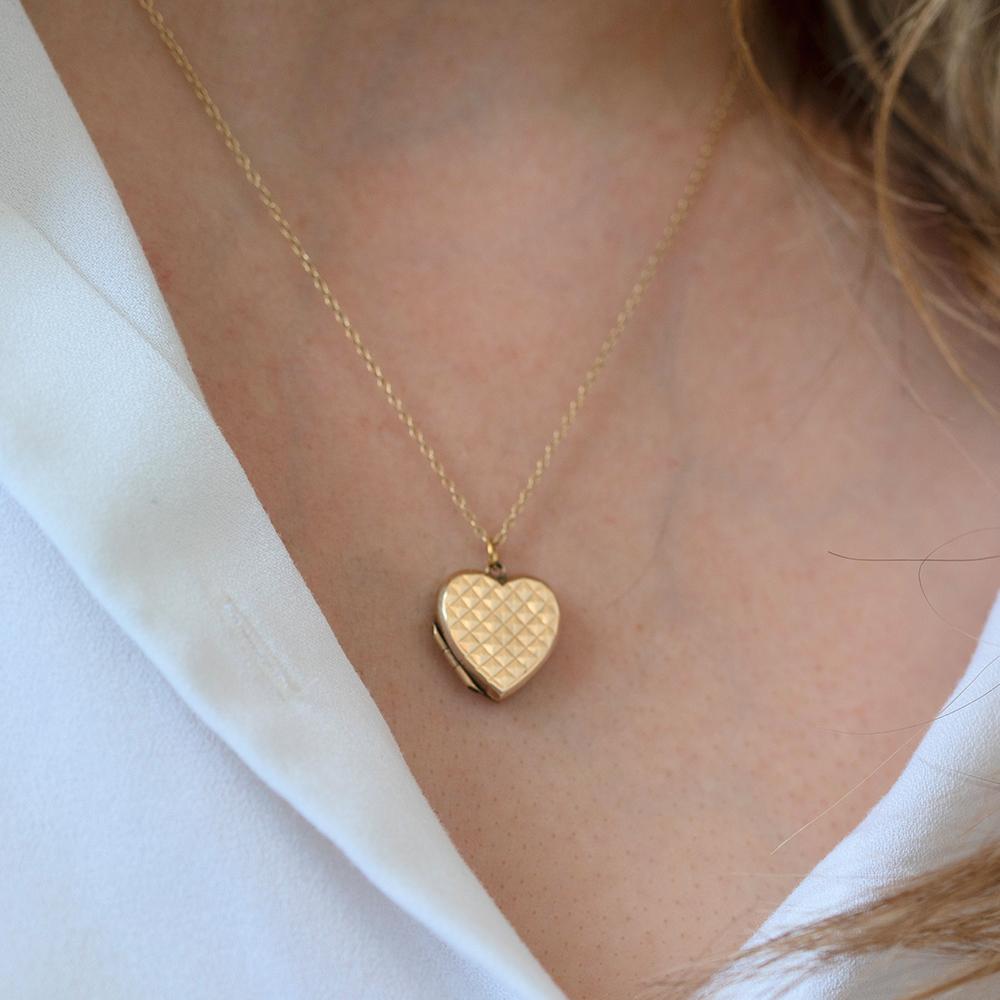 This charming vintage heart locket is crafted in 9ct gold and features a bold, faceted geometric pattern across the front. The repeated pyramid-like texture gives the surface a striking, light-catching finish—both tactile and reflective, making it a