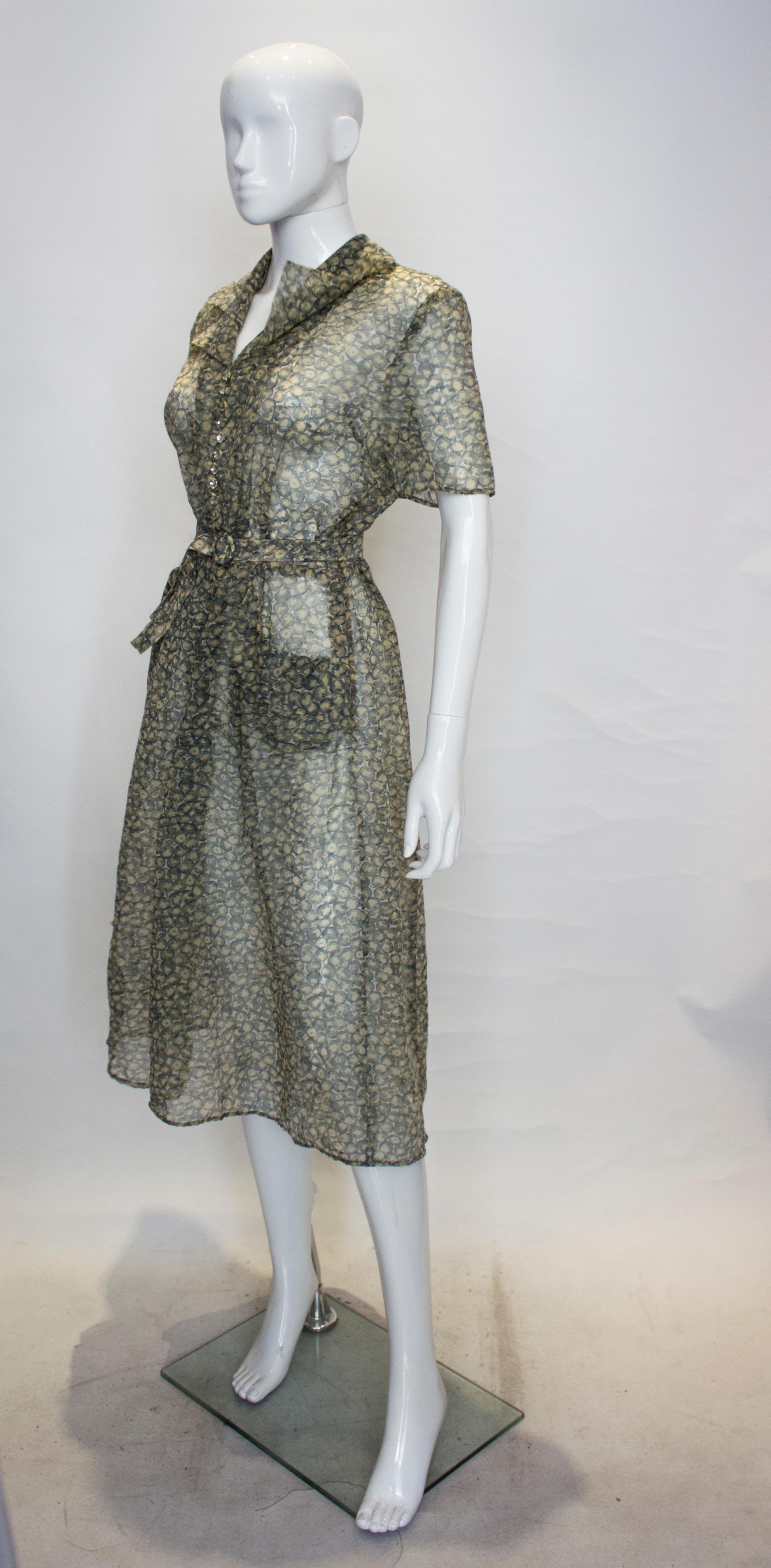 A pretty Summer dress from the 1940s. The dress has an interesting double collar and button detail on the front. It has a side zip opening, short sleeves a self fabric belt  and 2 pockets at hip leval. 