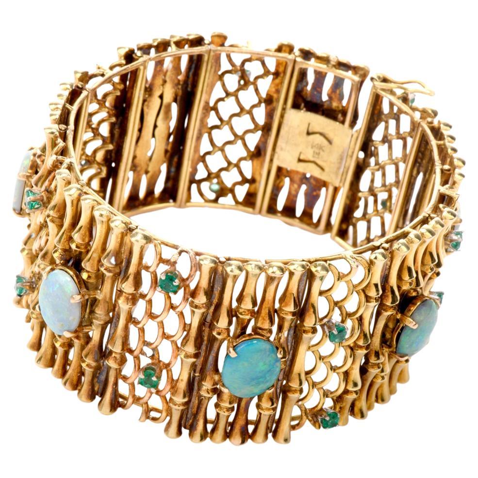 his vintage 1940's Opal and Emerald bracelet is crafted in 14 karat yellow gold. Incorporating  Art Nouveau motif links of waves and bamboo and exposing 7 Genuine cabochon shaped Opals approx. 16.30 carats, this piece is complemented by 14 genuine