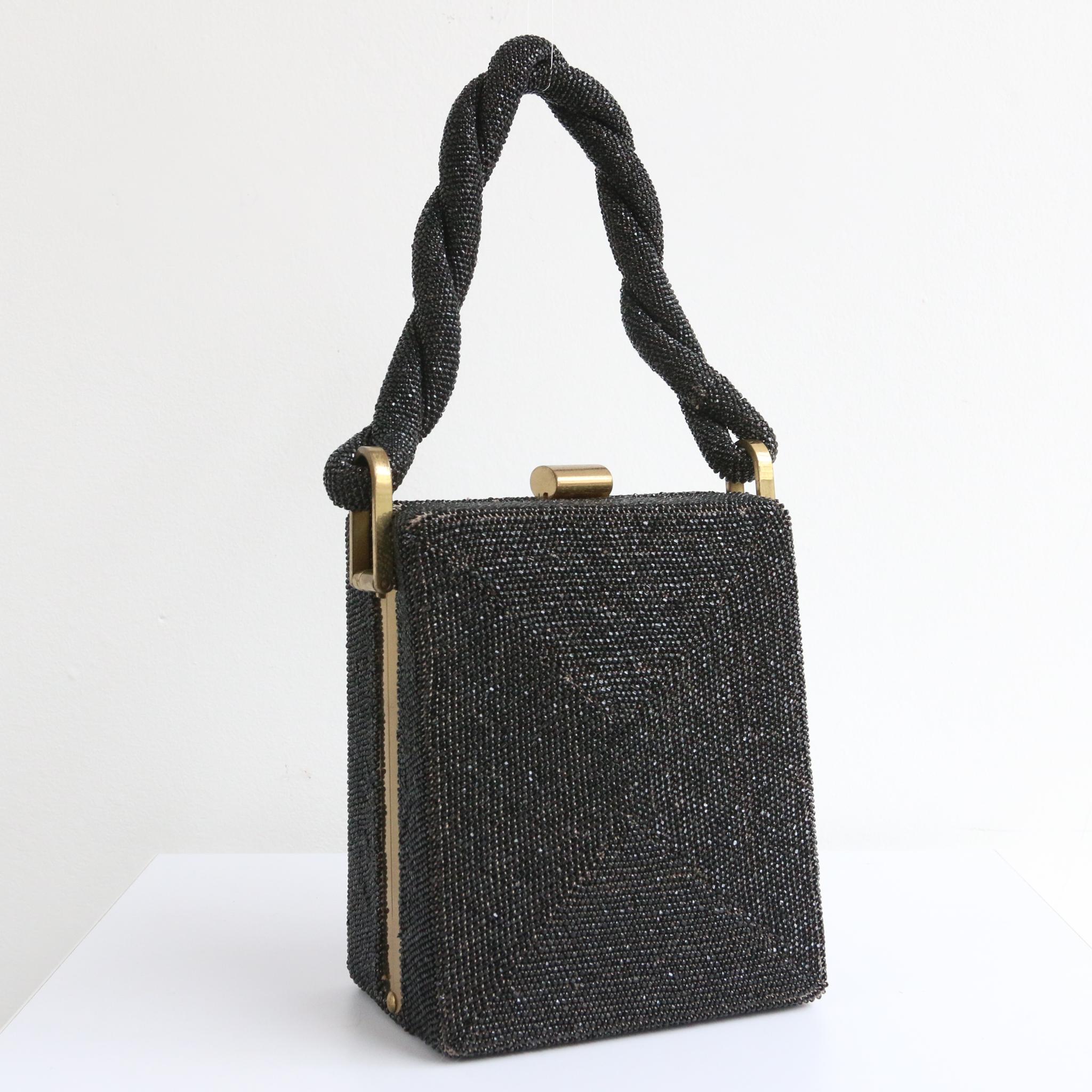 This breathtaking 1940's large rectangle box bag, with brass metal features is the perfect finishing piece to your ensemble. 
The rectangle shape of the bag, box an exterior of black glass faceted beads, set off by a brass metal frame and a central