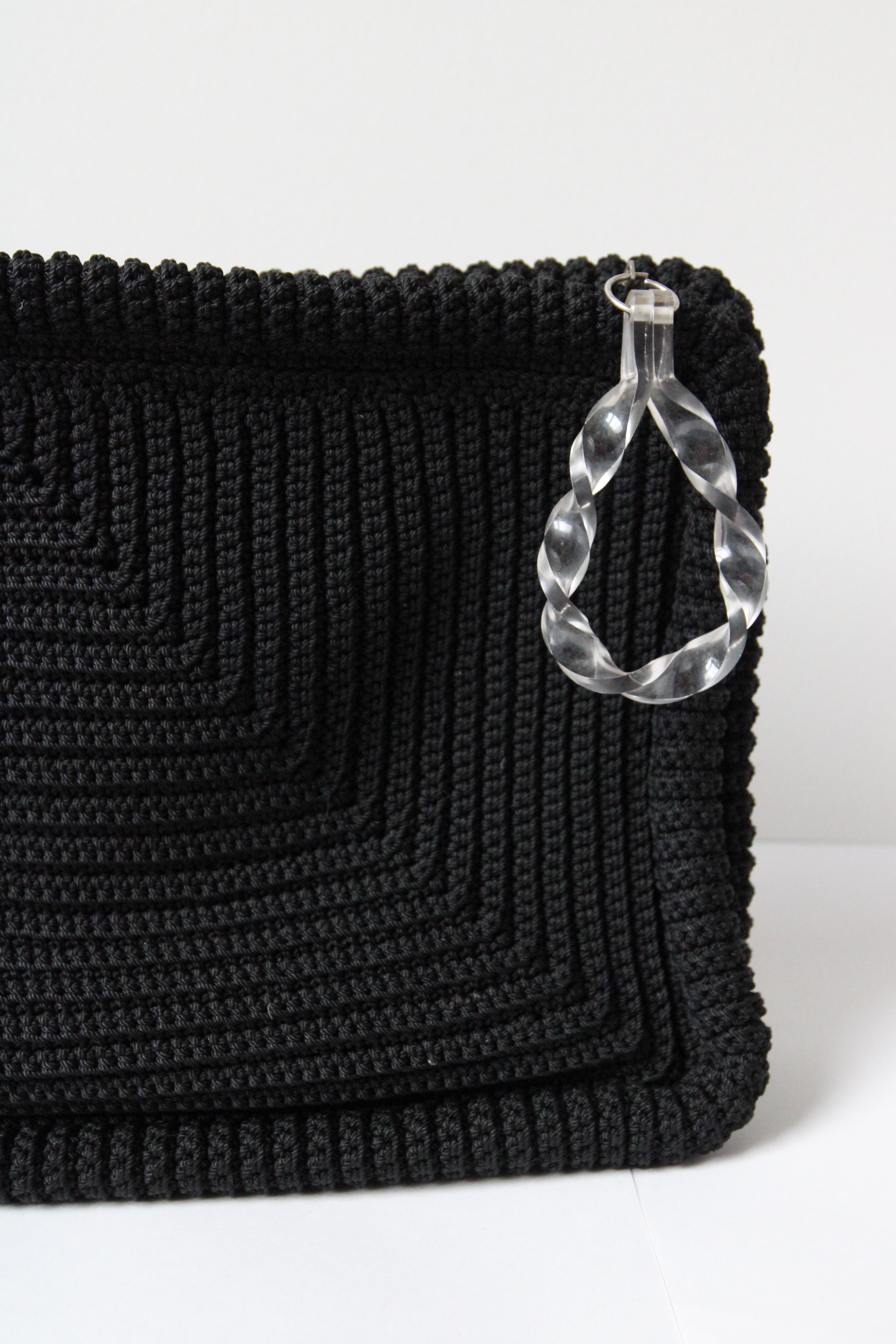 This beautiful and rare large 1940’s clutch bag, made up of black crochet stitches, in a raised pattern with circular crochet detailed frames, is the perfect statement accessory.  

The rectangular shape of the bag opens with a metal zip fastening