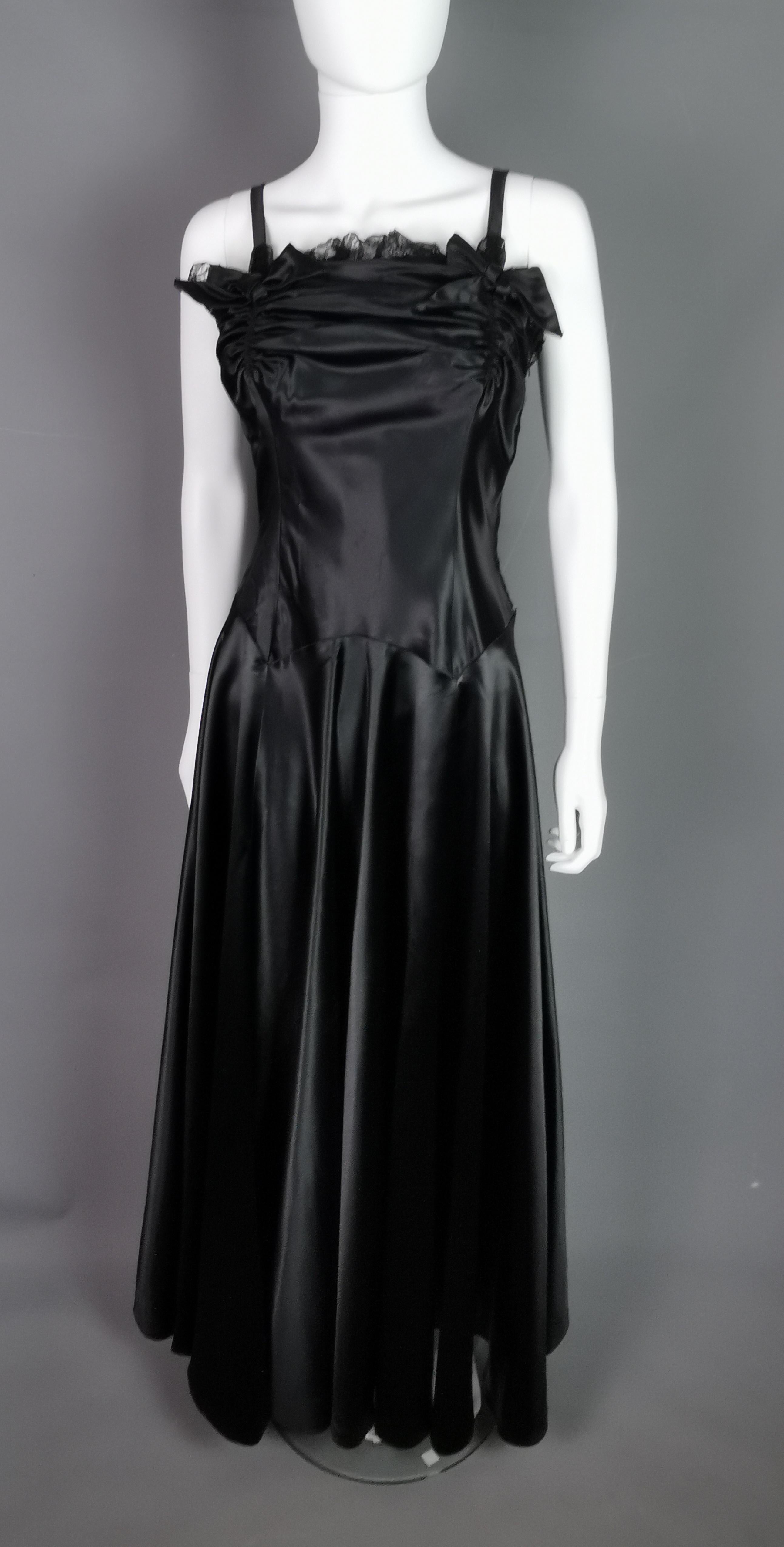 Cette rare robe de soirée vintage des années 1940 est vraiment l'étoffe dont les robes sont faites !

D'une superbe conception, cette robe très flatteuse pour la silhouette est confectionnée dans un satin liquide d'un noir profond qui tombe et coule