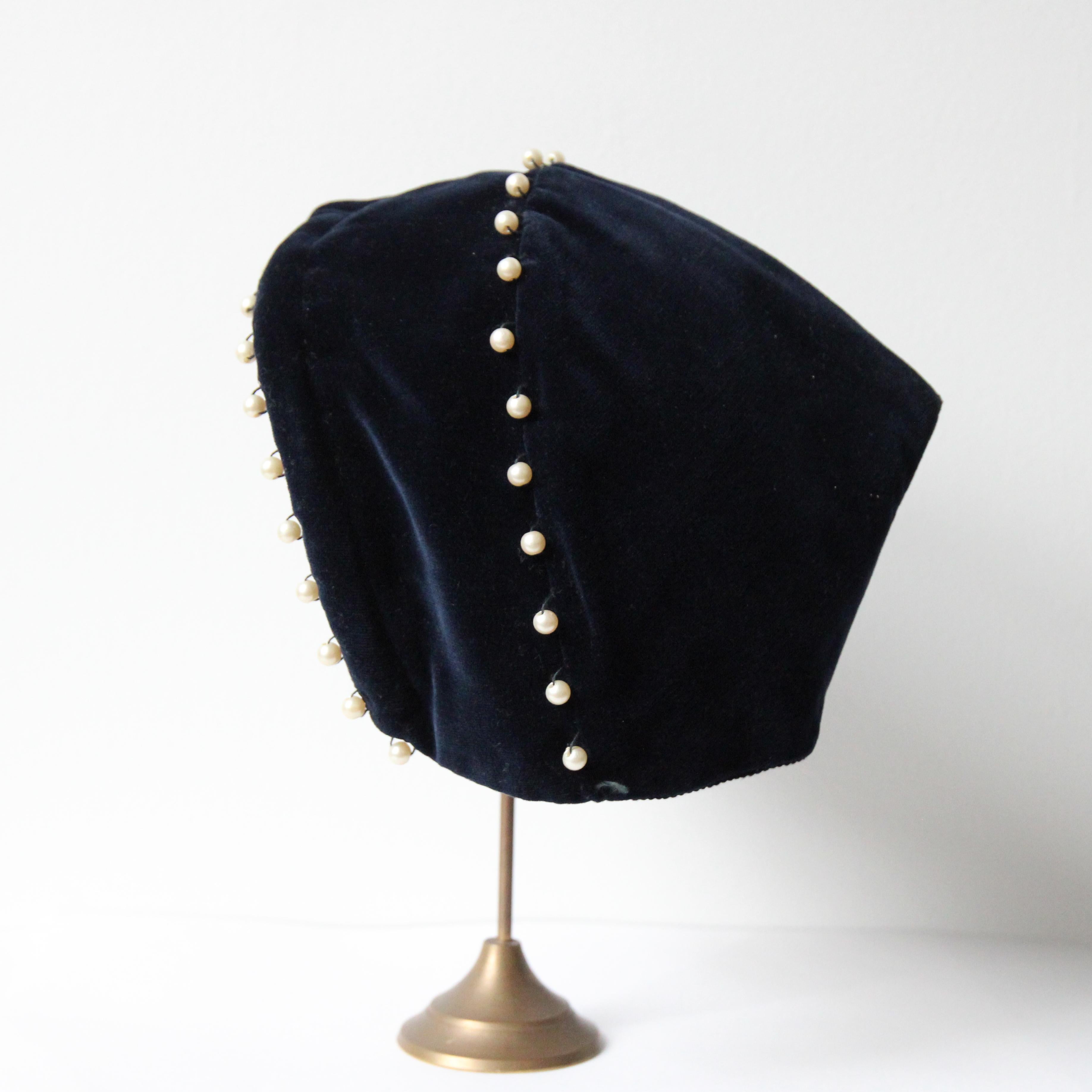 This wonderful 1940's navy blue velvet and pearl decorated hat and matching bag set, are the perfect ode to the winter season.

The pixie design of the hat, boasts a rounded wire frame along the brim of the hat, which is accented by sewn pearlescent