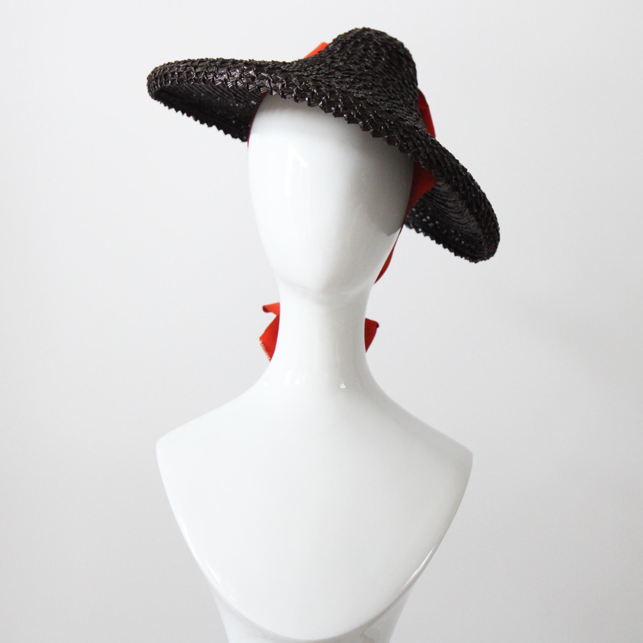 Este fascinante sombrero de paja de chocolate amargo de los años 40, con un brillante lazo naranja, es la pieza perfecta para tu vestuario de temporada. El ala ancha y estructurada presenta un pequeño cuello vuelto hacia abajo, que atrae la mirada