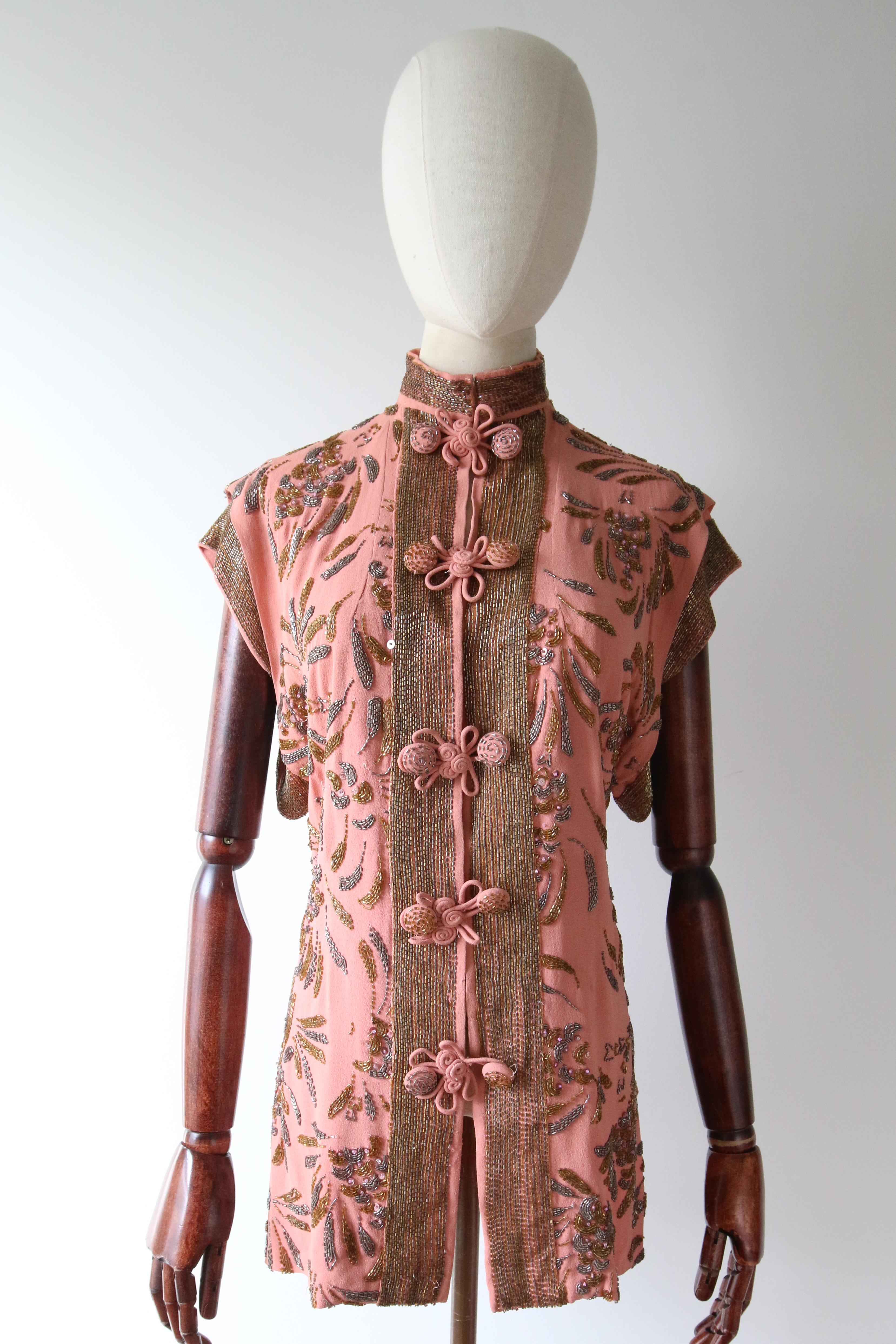 A beauty to behold. This original 1940's crepe silk blouse, rendered in the most incredible blush silk, and embellished with ornate beadwork in shades of gold and gunmetal grey, with sparkling pink sequins and pink glass beads, in a floral design