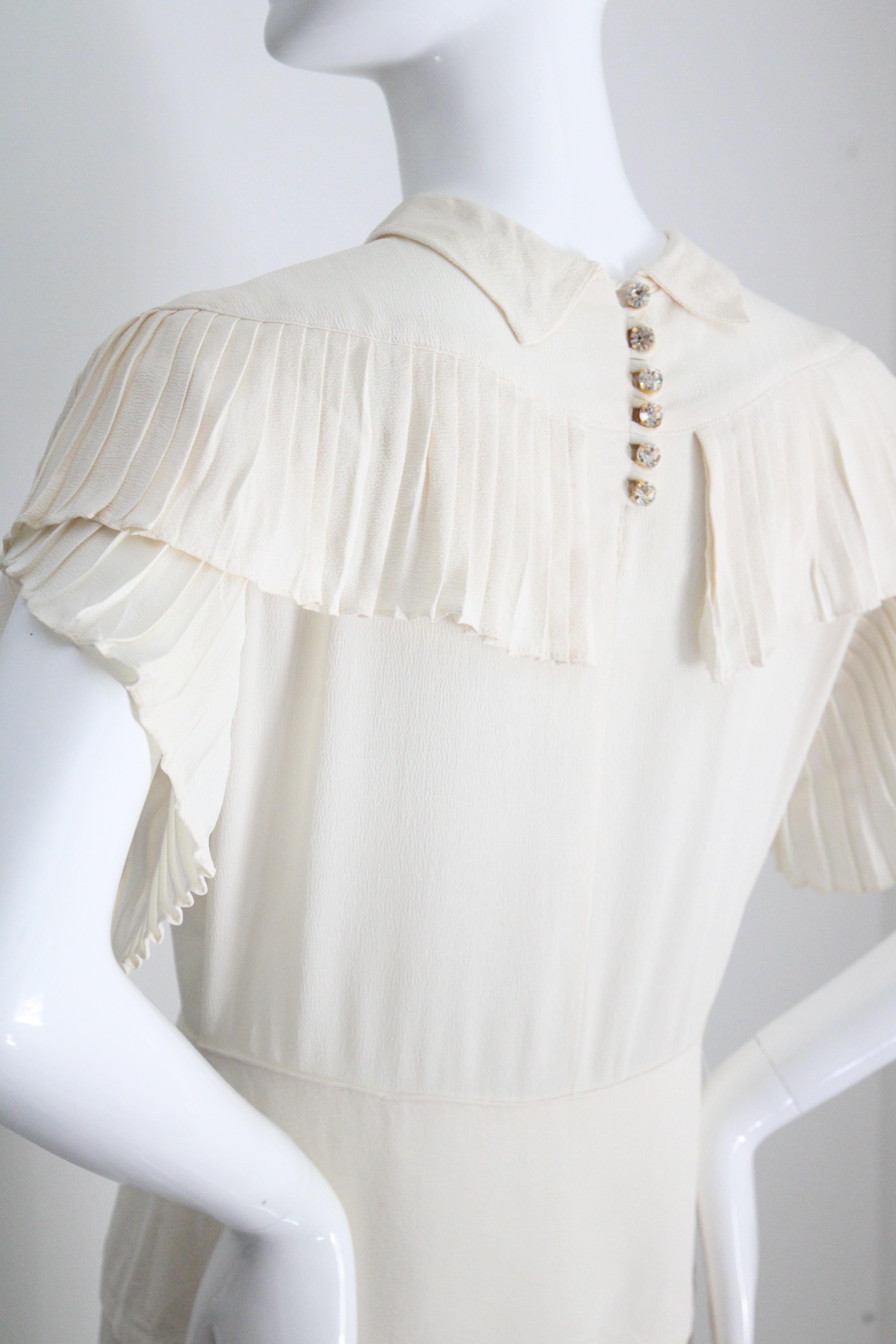 Questo abito anni '40 davvero ipnotico, realizzato nella più morbida tonalità di seta crepe e arricchito da delicati dettagli a pieghe, è il perfetto pezzo senza tempo da aggiungere alla tua collezione vintage.  

La scollatura arrotondata