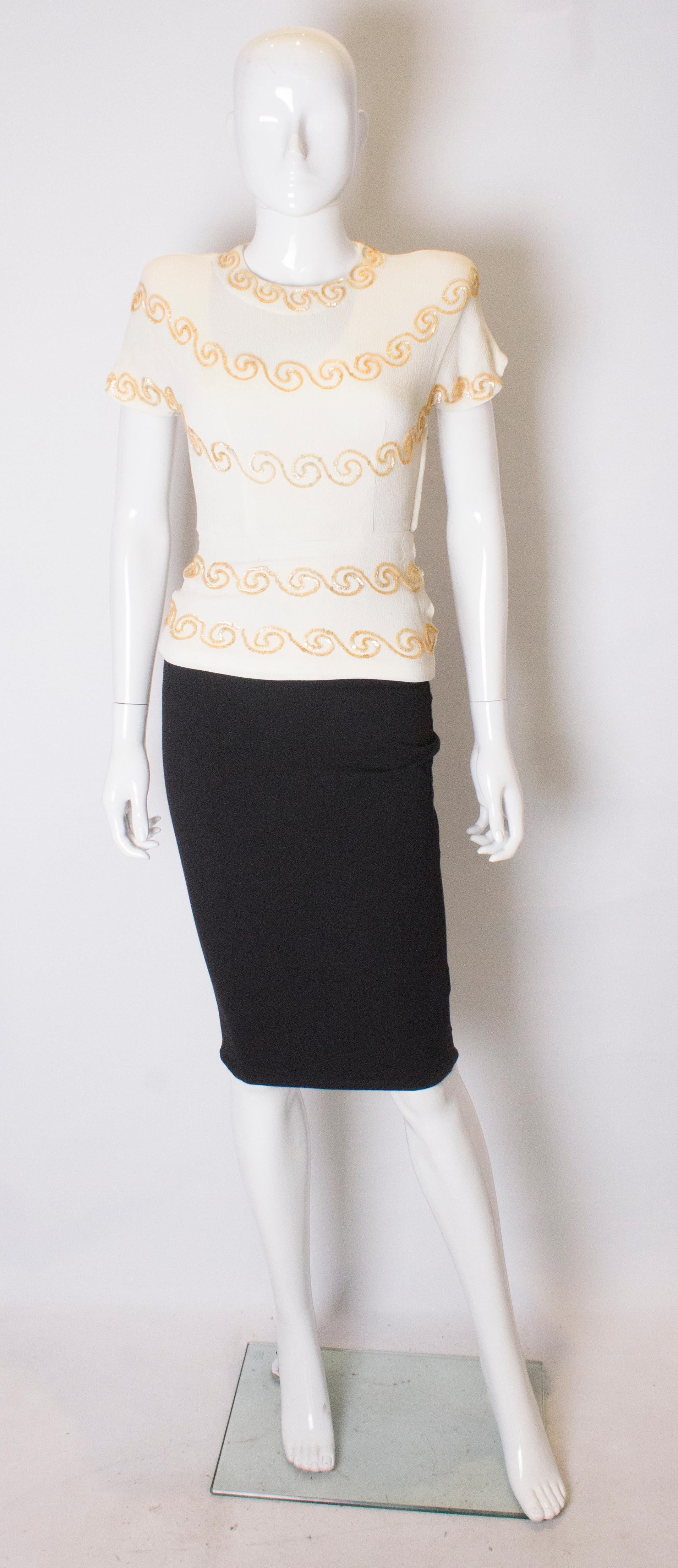 A head turning ivory crepe top by Marberl of California. The top is decorated with gold colour sequins, has cap sleaves, a central and side zip plus a peplum waist.