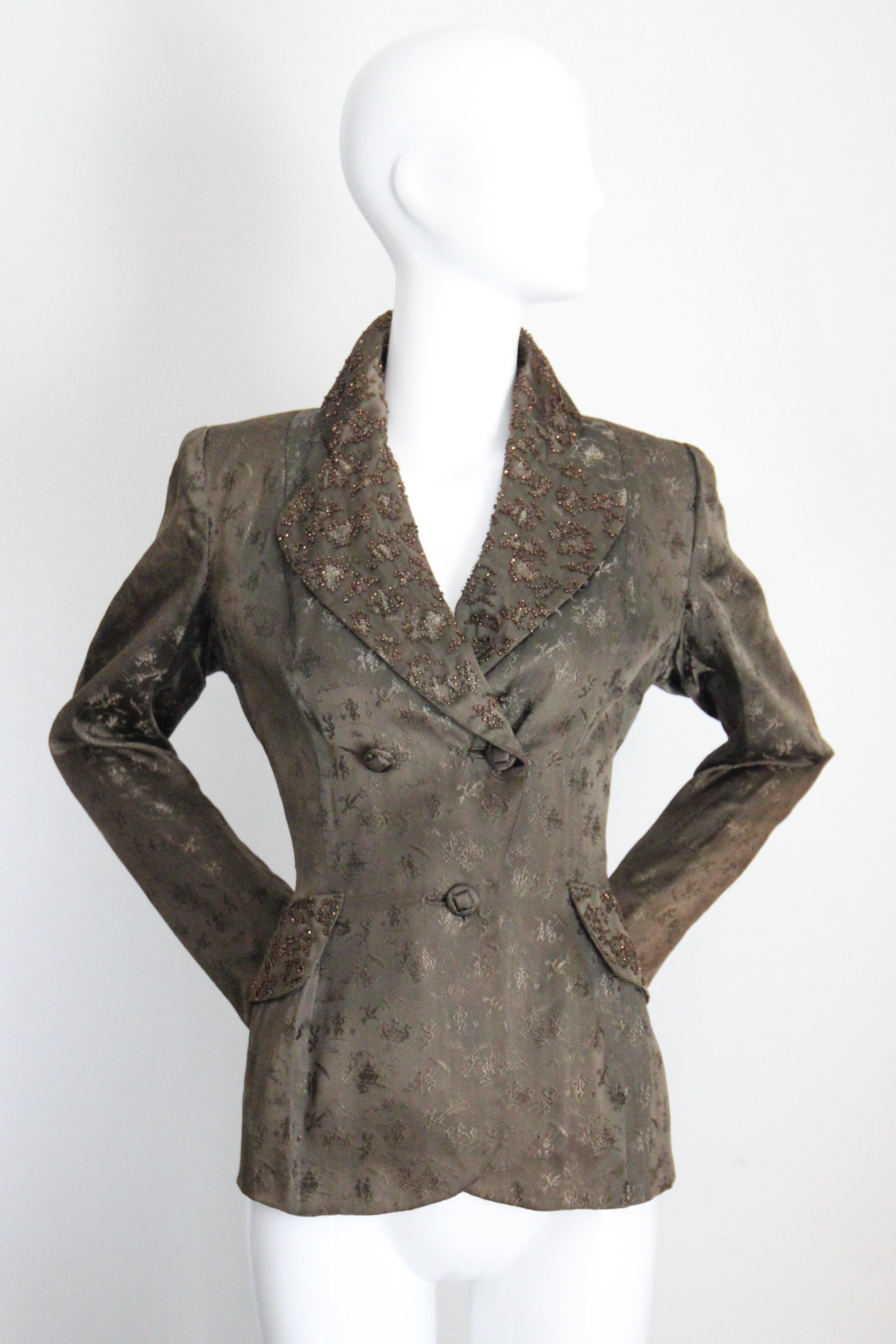 Questa splendida giacca in broccato di seta verde Secret Garden degli anni '40, con un motivo di scene di paese accentuato da perline colorate lungo i revers e le finte tasche, è il pezzo perfetto per il tuo guardaroba quotidiano.

La scollatura a V