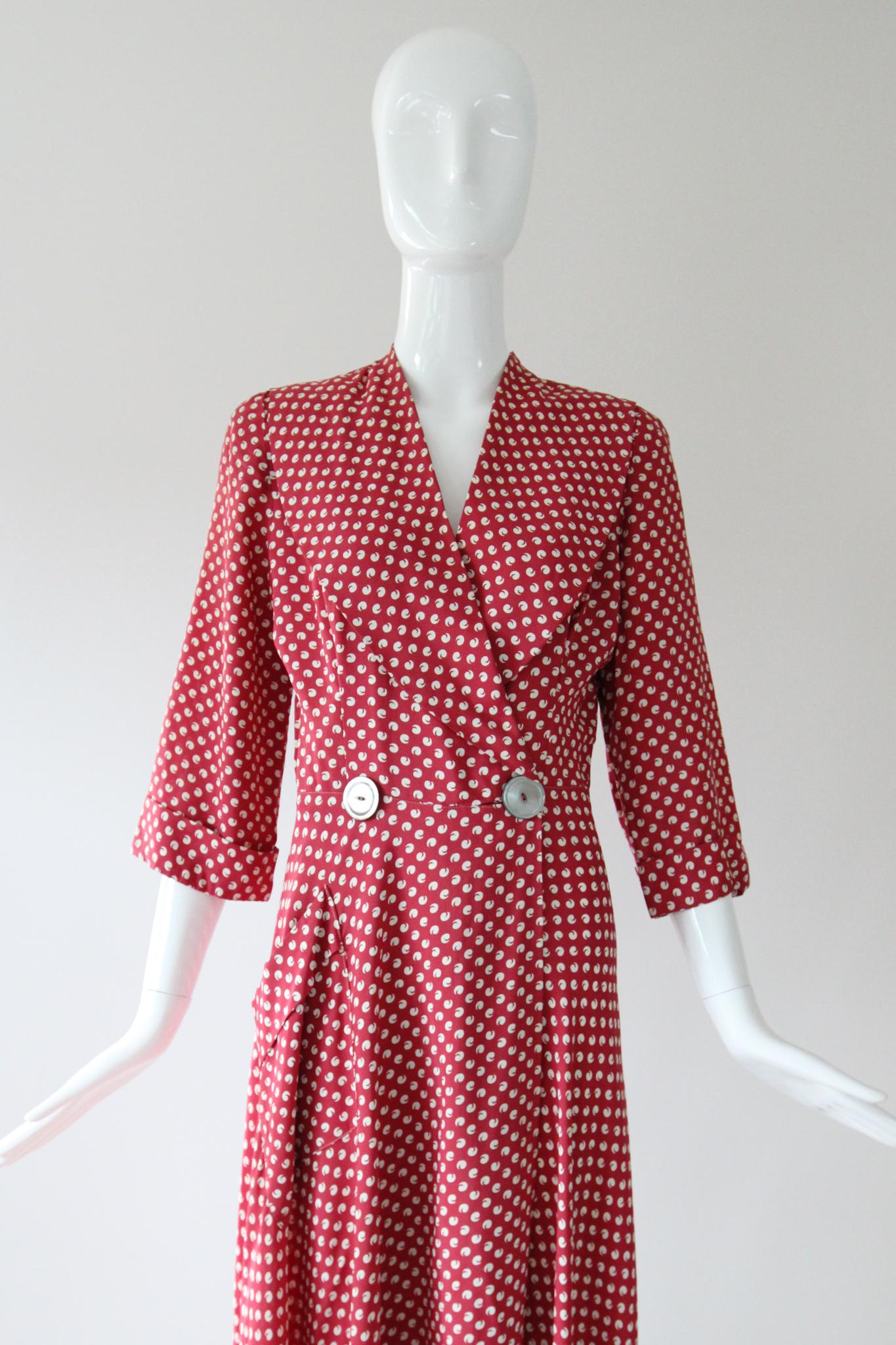 This original vintage 1940's berry red cold rayon robe with a pattern of white apostrophes, is the perfect addition to your loungewear collection. 

The V shaped neckline is framed by wide shawl cut lapels, which accent the cross-over cut along the