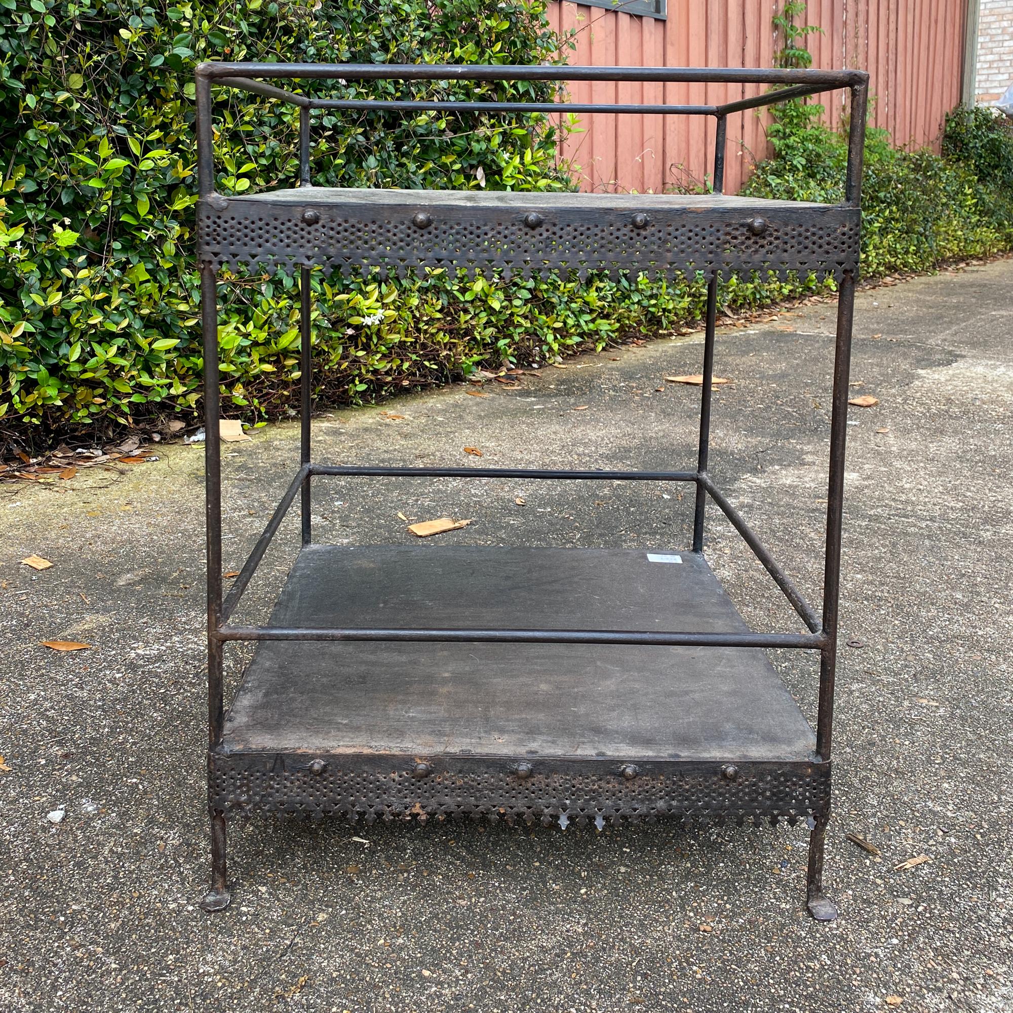 This charming, 1940s French metal table has two levels, both with a pierced metal apron detail which is very gothic in style. The simple lines allow the decoration to take center stage and is perfect for use as a plant stand or small side table. The