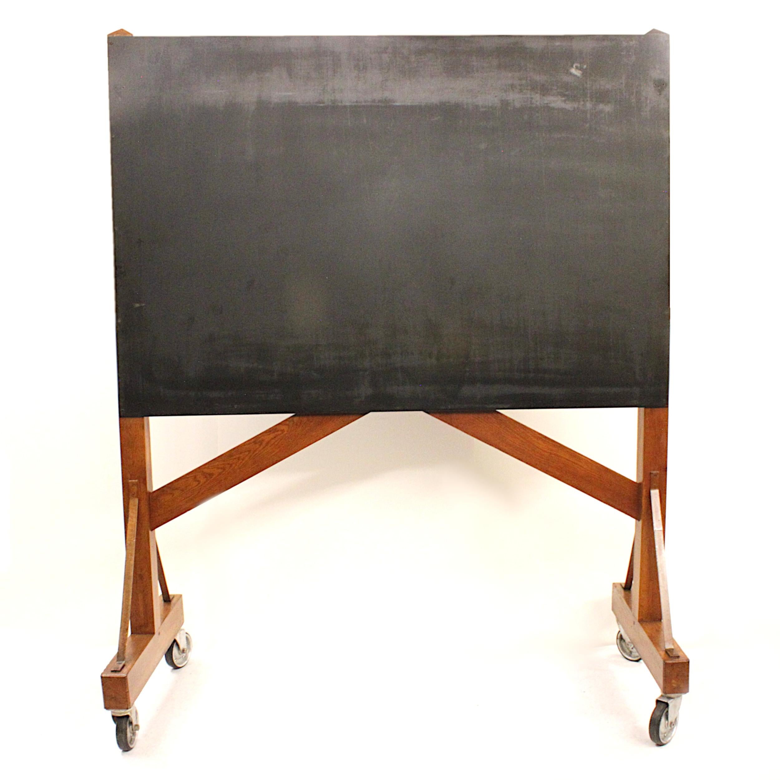 Spectacular 1940s vintage blackboard. Blackboard features a heavy-duty, solid-oak frame with steel braces and aluminium casters. The blackboard itself is actually a solid sheet of steel with blackboard treatment allowing you to both write with chalk