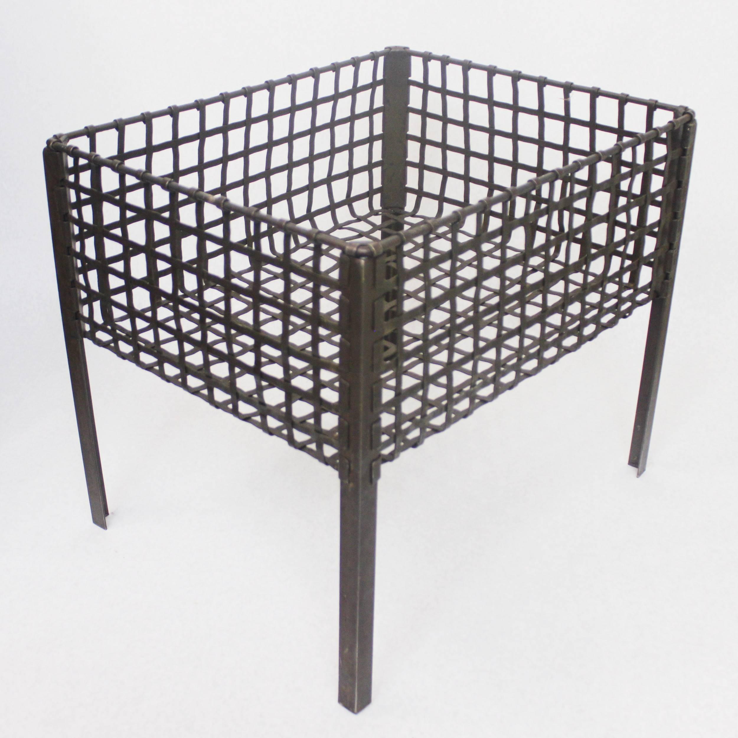 These 1940s era metal baskets came out of an Illinois state penitentiary manufacturing facility. Baskets feature a 8.5 inch deep woven steel receptacle atop four angle-iron legs finished in a dark, army green paint. Baskets have been given a fresh
