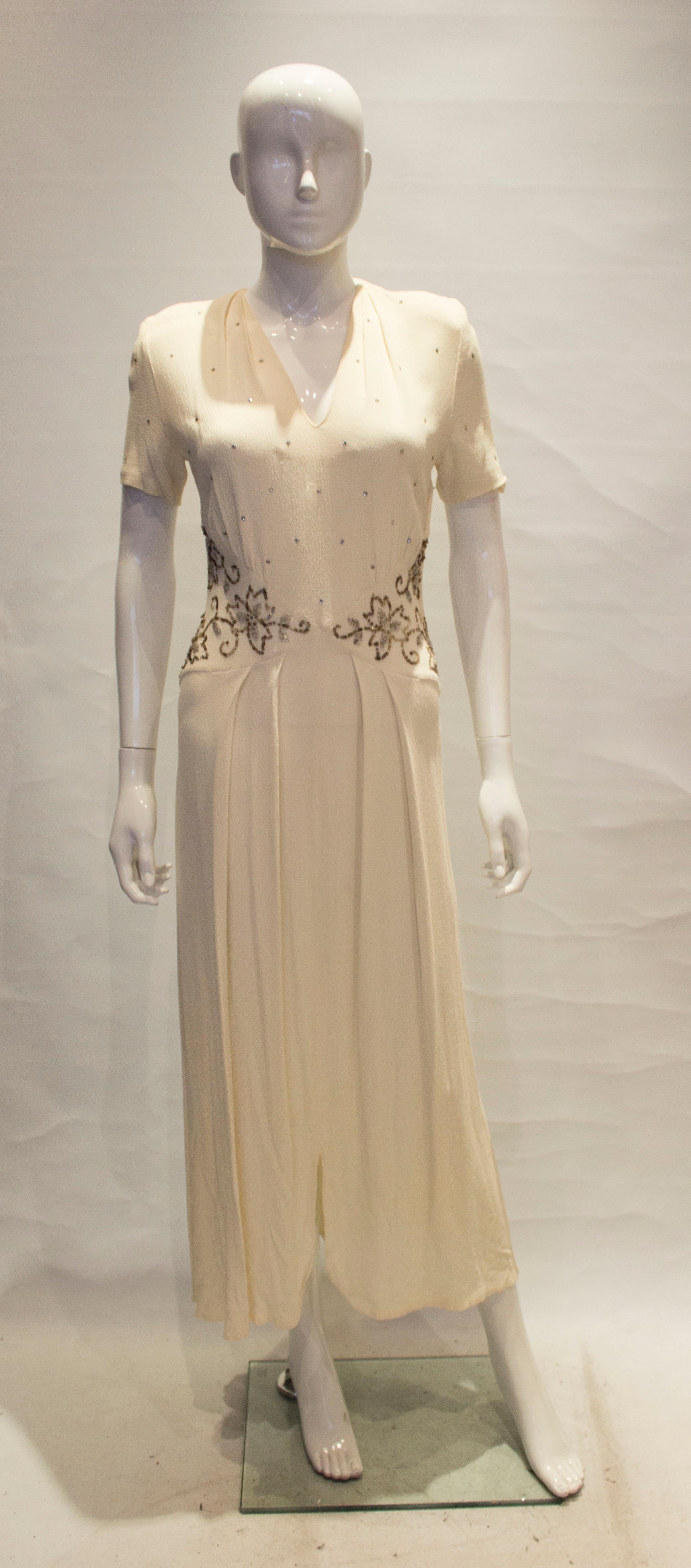 A chic vintage crepe dress dating from the 1940s. The dress has a v neckline , short sleaves and 
pleats. There is sequin detail at waist leval front and back.