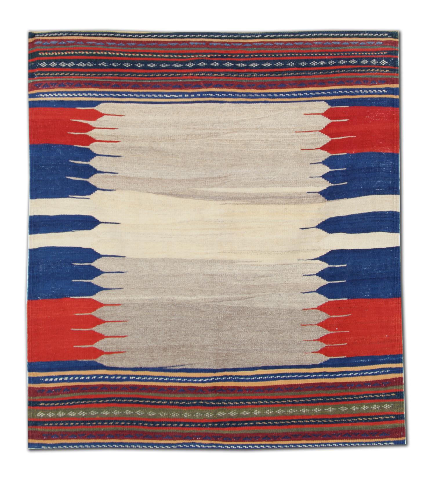 Dieser handgefertigte Wollteppich aus den 1940er Jahren ist ein eindrucksvolles Beispiel für Stammeskunst. Er zeigt ein traditionelles quadratisches Sofreh-Muster, das in erdigem Beige, tiefem Rot, Marineblau und leuchtendem Blau gewebt ist. Flach