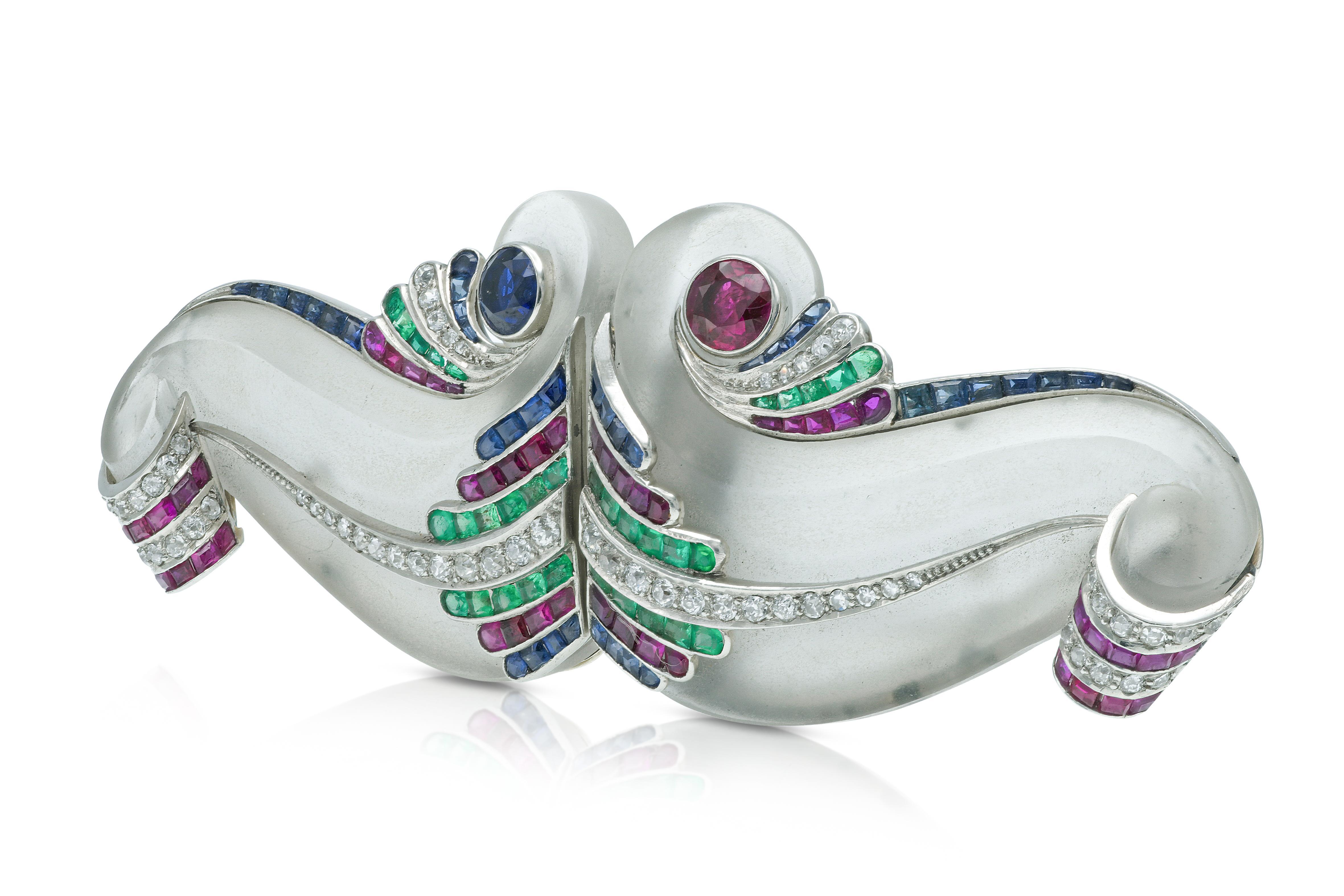 Finely crafted in 14k white gold with 2 carved Rock Crystals, Diamonds, Rubies, Emeralds, and Sapphires.
The brooch separates into two small clips.
Circa 1940s
Brooch 1 1/8 x 3 3/8 inches
Individual clip 1 1/8 x 1 11/16 inches