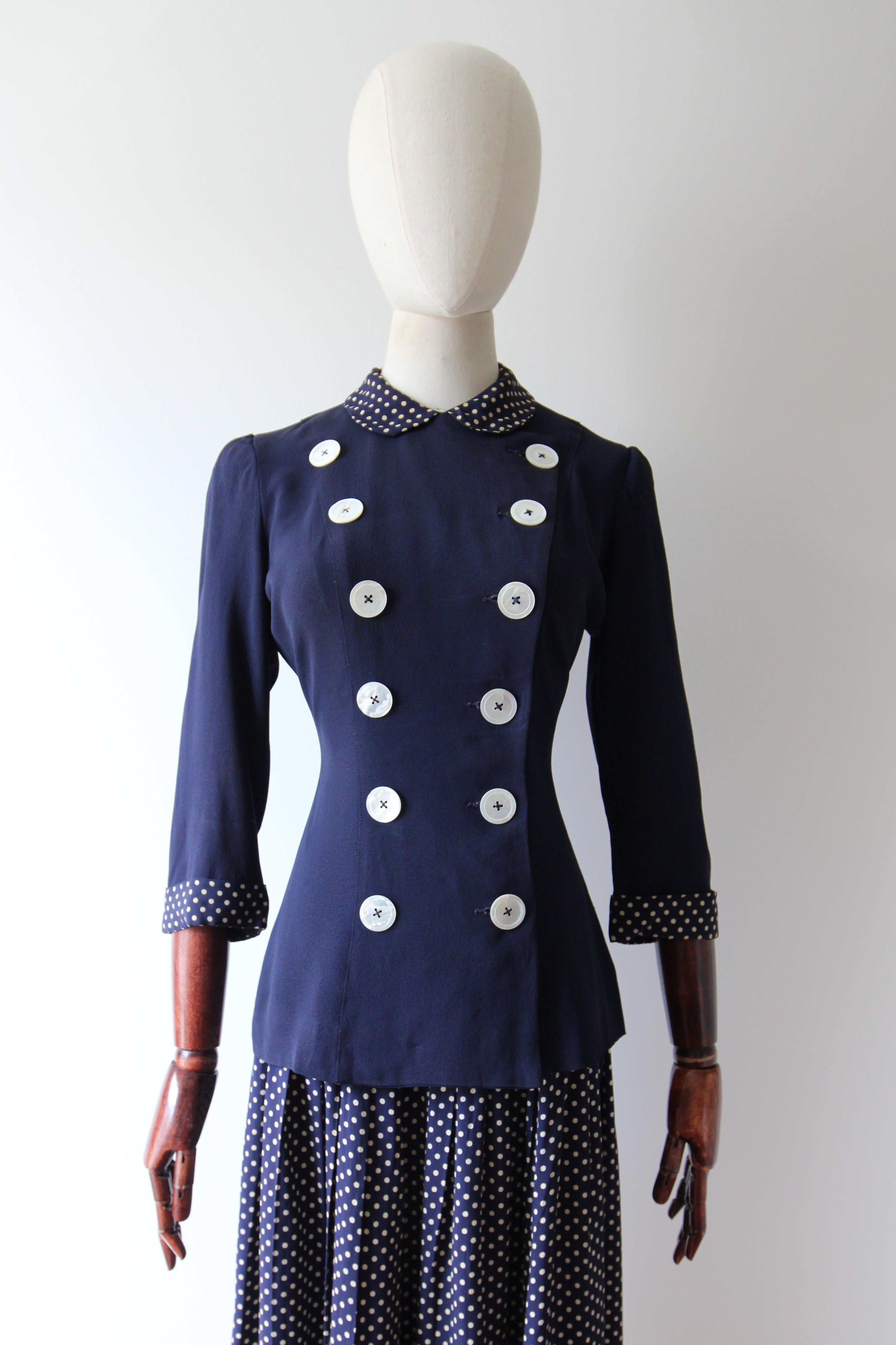 Realizzato nella tonalità più intramontabile del rayon blu navy e impreziosito da accenti di seta crema e blu navy a pois, questo set vintage originale degli anni '40, composto da gonna e giacca in seta, è l'insieme perfetto per il tuo guardaroba