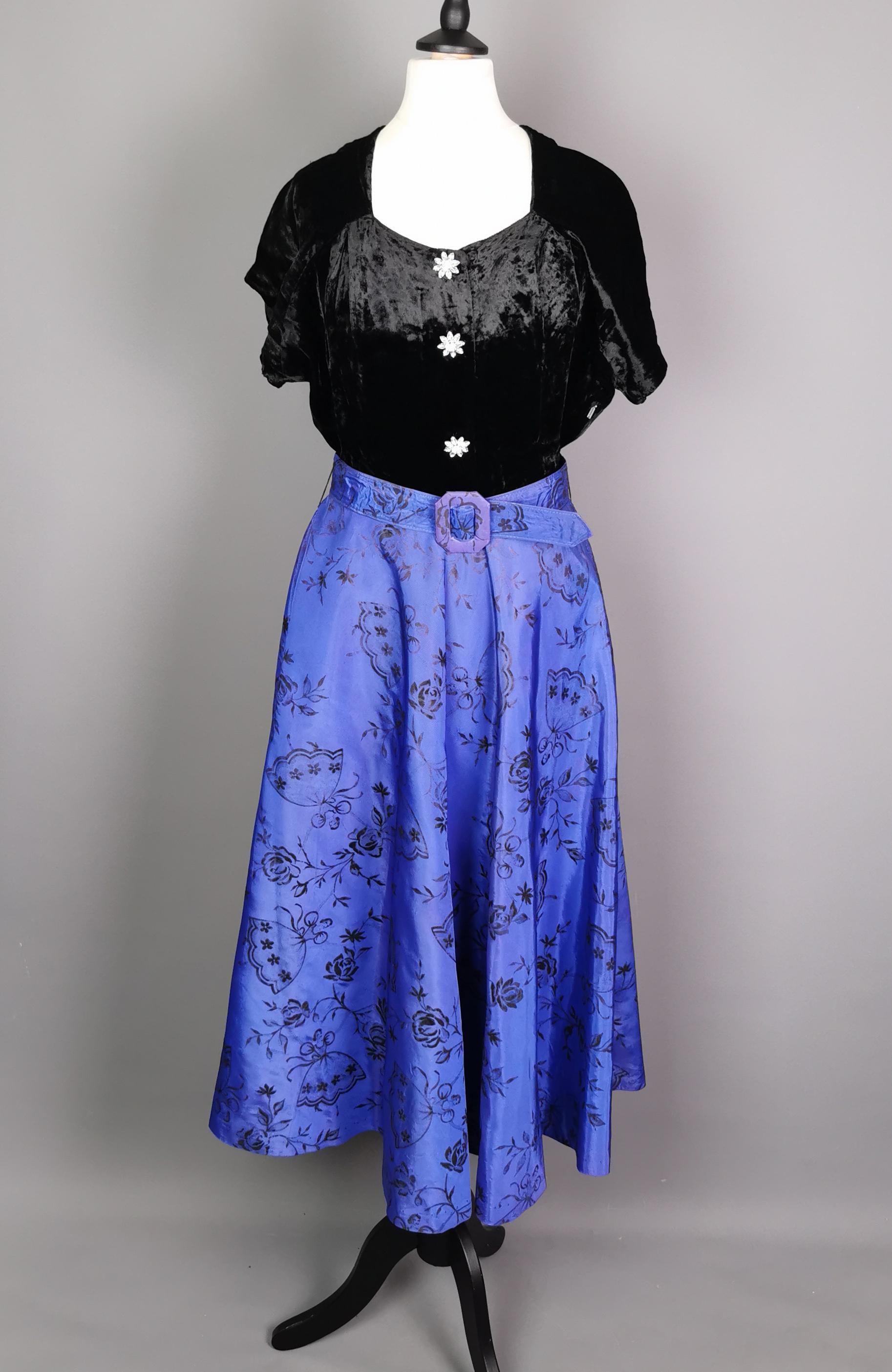 A superb, gorgeous vintage late 1940s evening dress.

It has a sumptuous black silk velvet bodice with a soft sweetheart neckline and faux buttons shaped like flowers in a diamante style.

The dress is nipped in at the waist with a full flared skirt