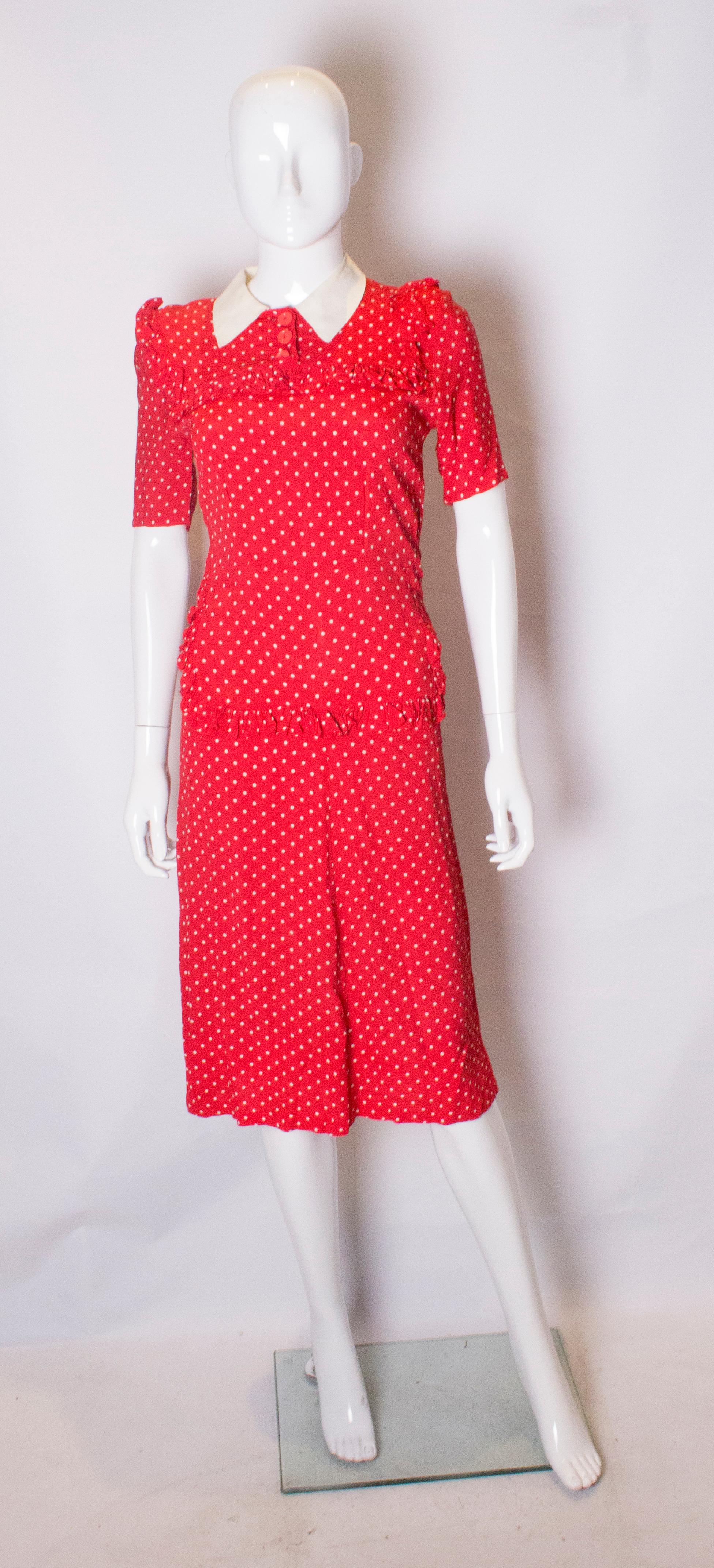 A pretty polka dot dress from the 1940s. 
The dress has a white collar, short sleeves , threee buttons on the front,  and a side popper opening.It has a frill trim around the bodice and the front , and small shoulder pads. 