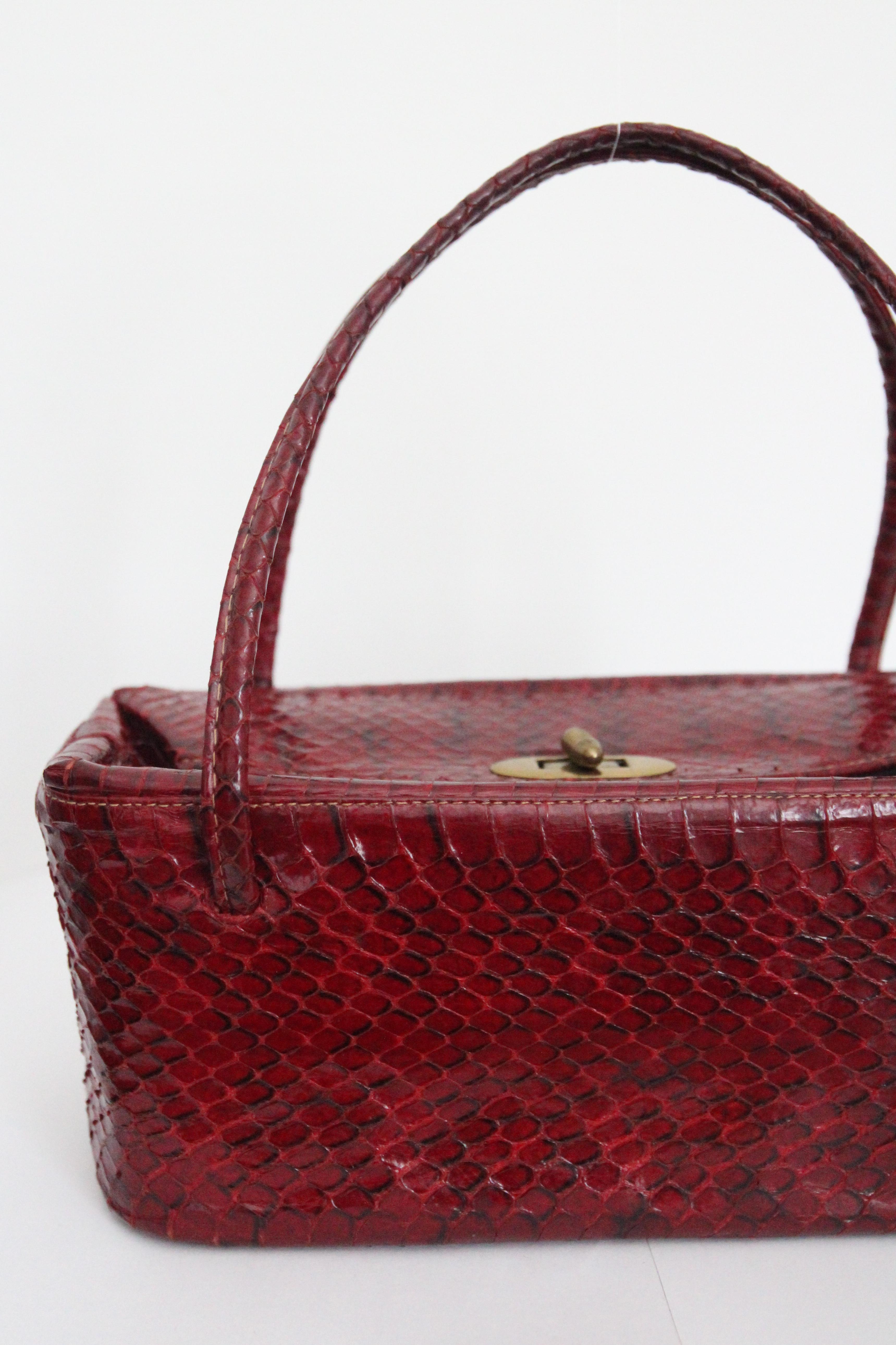 This beautiful textured 1940's box bag, rendered in a red snake skin, with gold toned metal hardware, is the perfect statement piece to add to your accessory collection. 

The beautiful box shape of the bag is accented by an envelop design top,