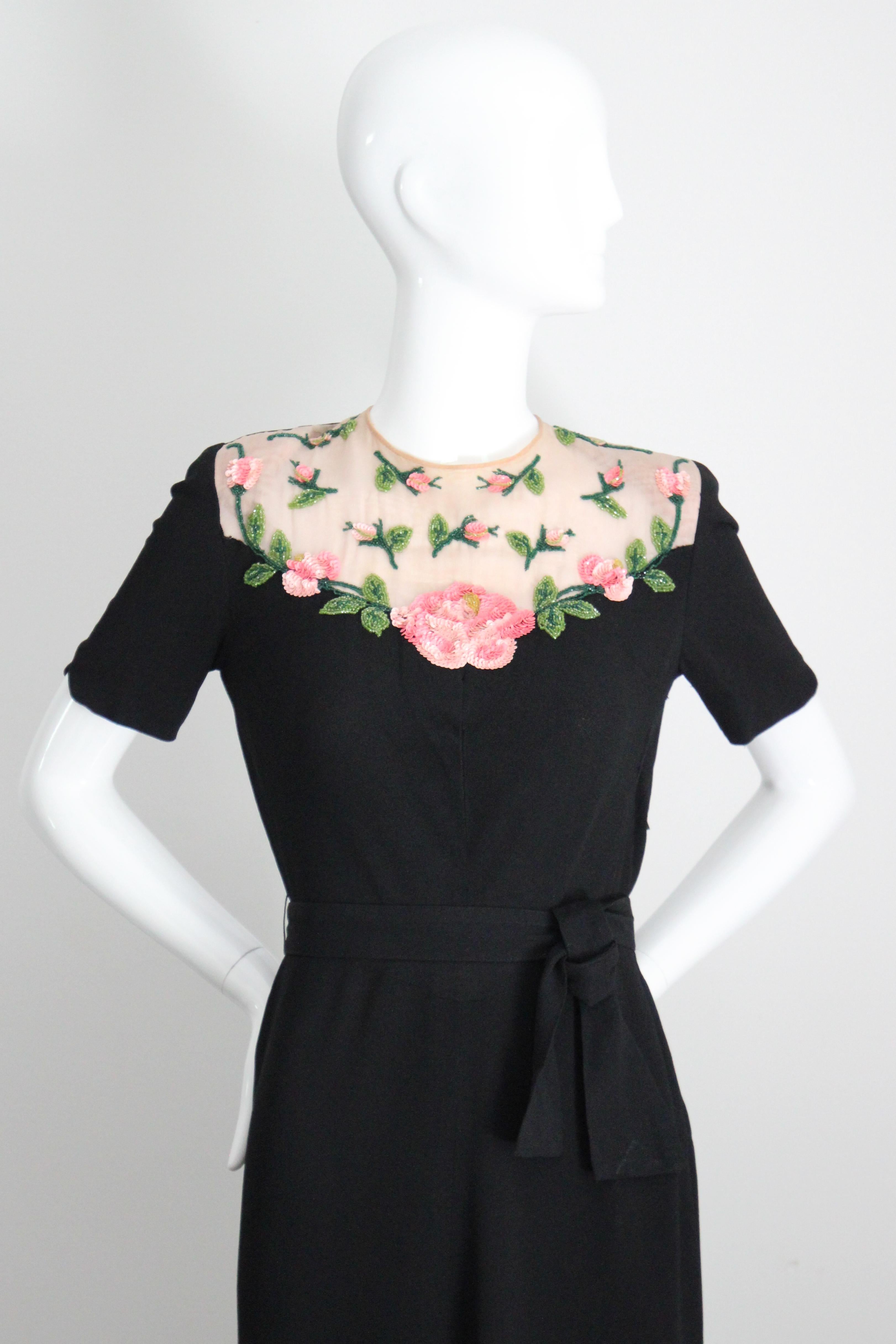 Dieses bezaubernde schwarze Seidenkleid aus Crêpe aus den 1940er Jahren, das mit rosa Pailletten und grünen und gelben Glasperlen in Form von Schleppen und verstreuten Rosen verziert ist, ist der perfekte Blickfang für Ihre Vintage-Sammlung.

Der