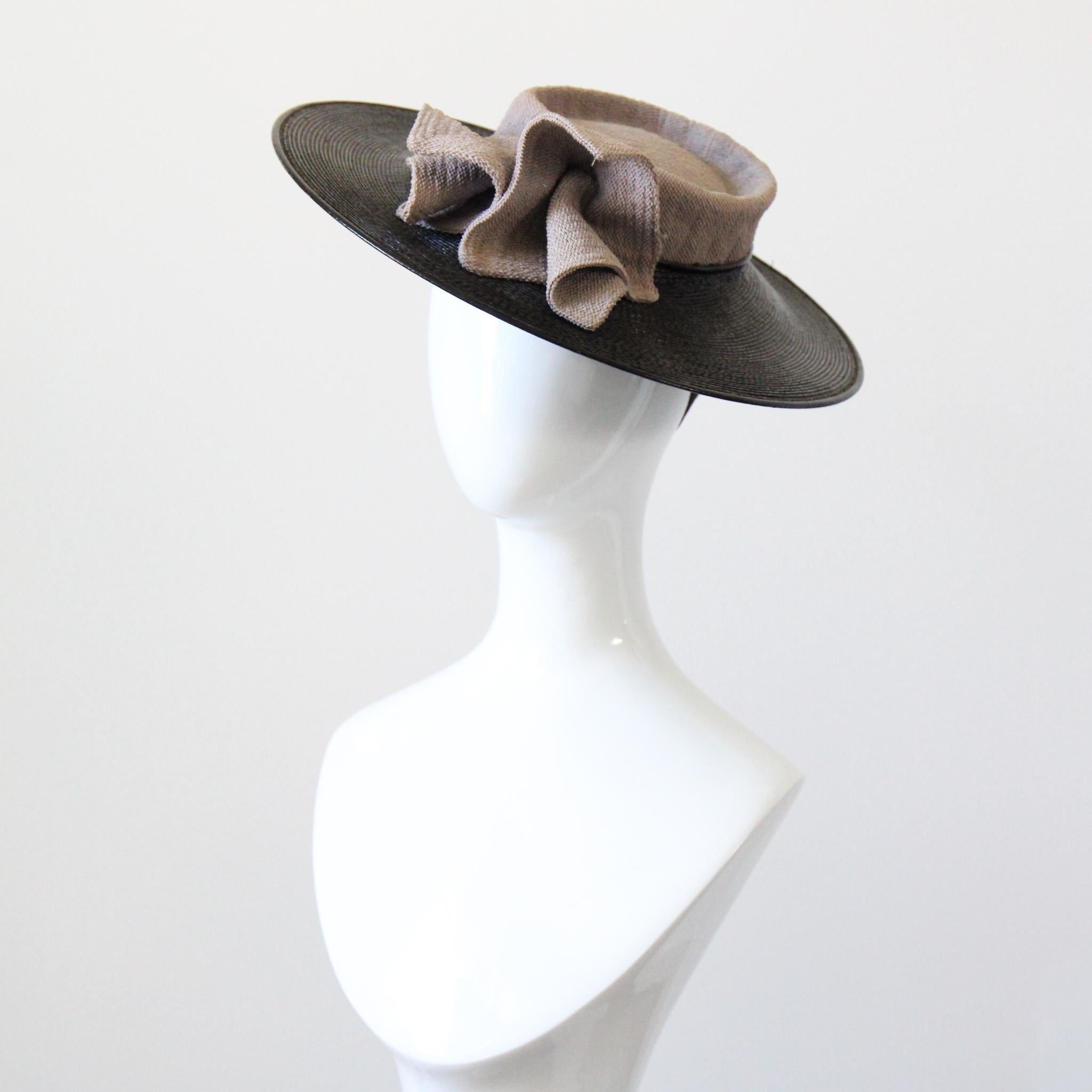 Questo incredibile cappello a tesa larga in paglia intrecciata degli anni '40, reso in una silhouette sartoriale e senza tempo, è l'aggiunta perfetta alla tua collezione di modisteria. La tesa in paglia nera lucida è orlata da profili in pelle nera