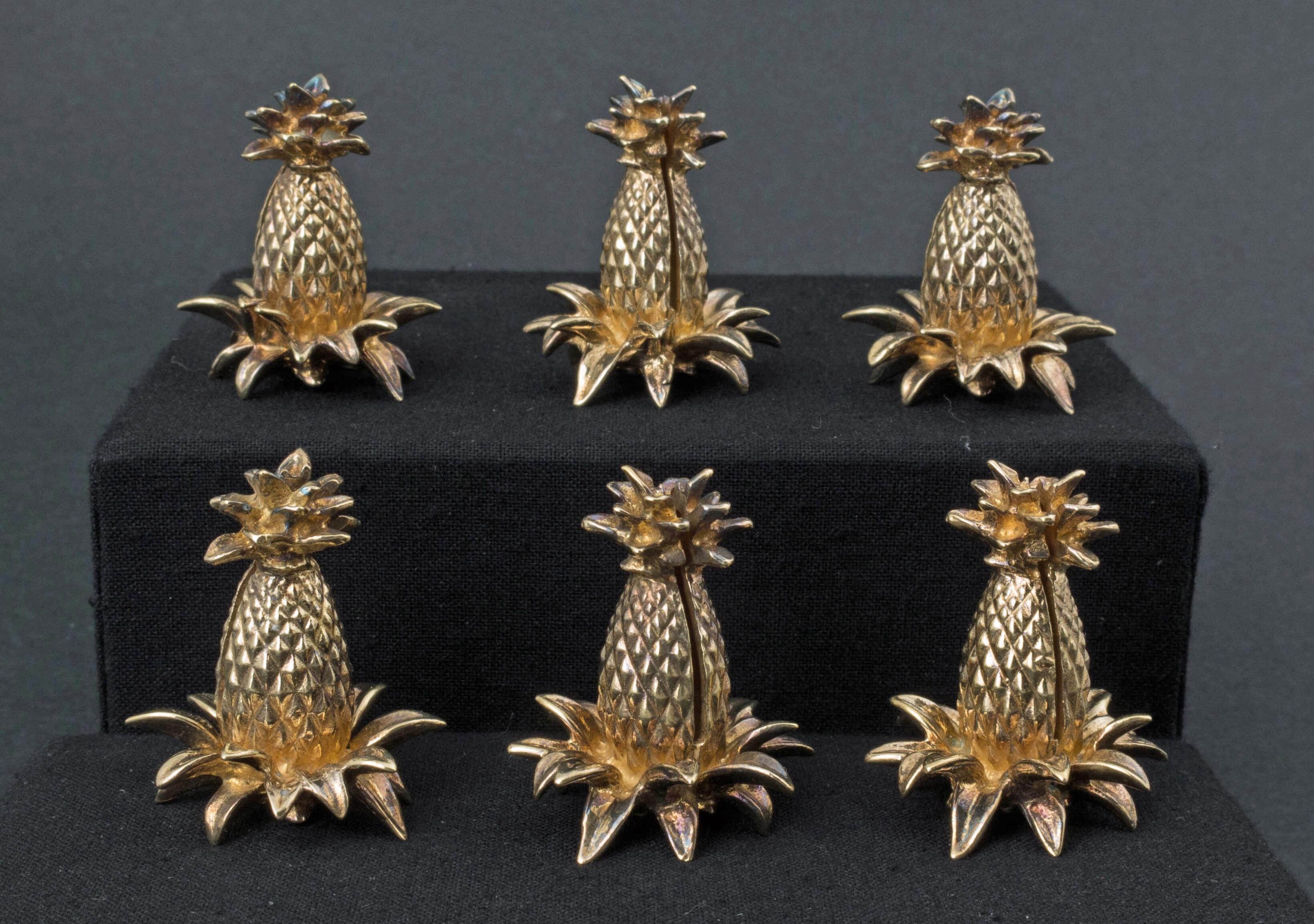 A wonderful set of six gilt silver pineapple form place card holders by Tiffany & Co., circa 1940s.

Crafted from gilt sterling silver, the charming placeholders are in the form of pineapples, complete with a spray of leaves to the base, and a