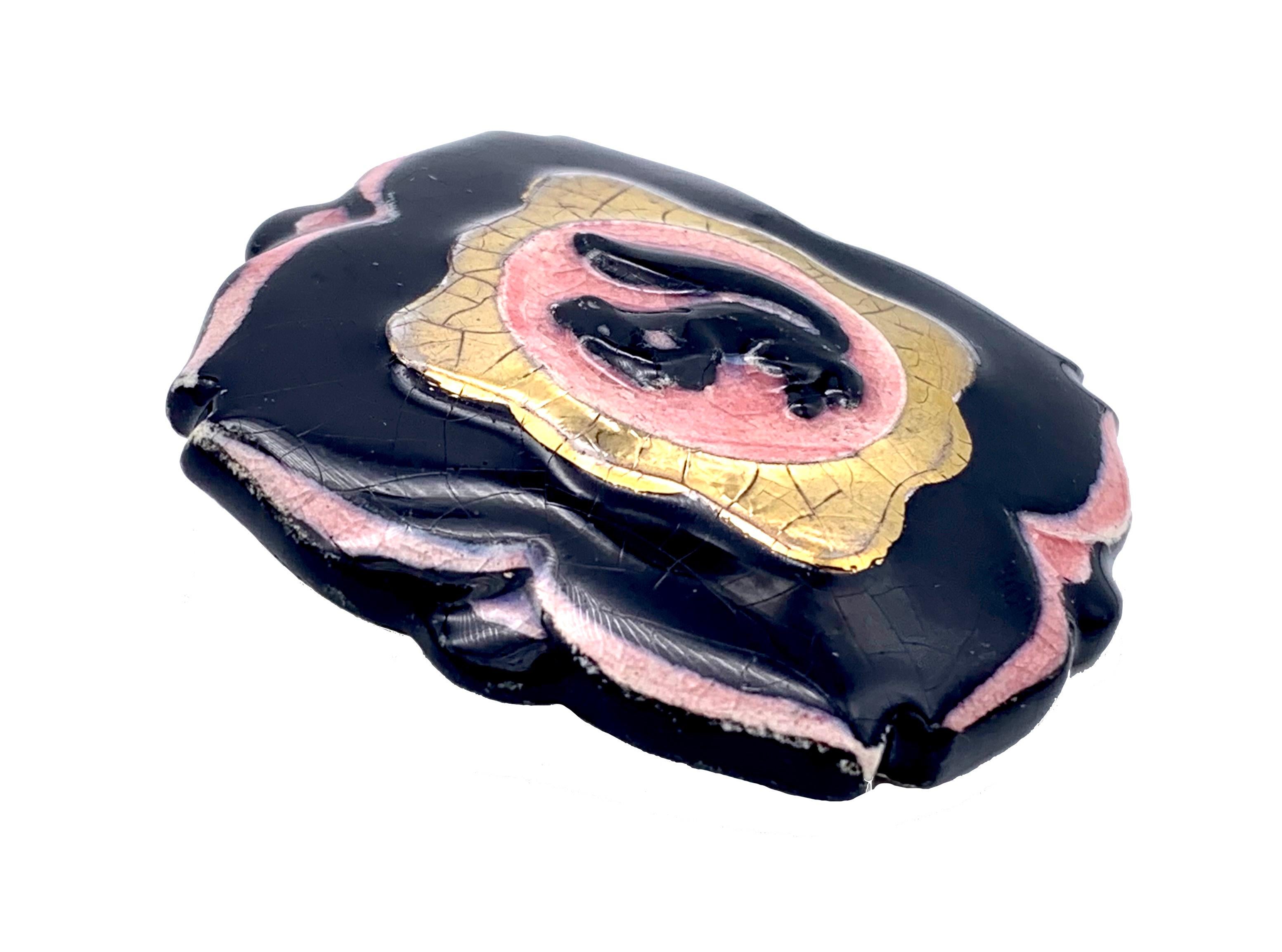This rare ceramic demi parure comprising a pair of clip-on-earrings and a brooch was handcrafted in Vallauris in the 1940's. The set is decorated with plack squirrels within a pink surround. The pink disks are surrounded by a gold coloured frame
