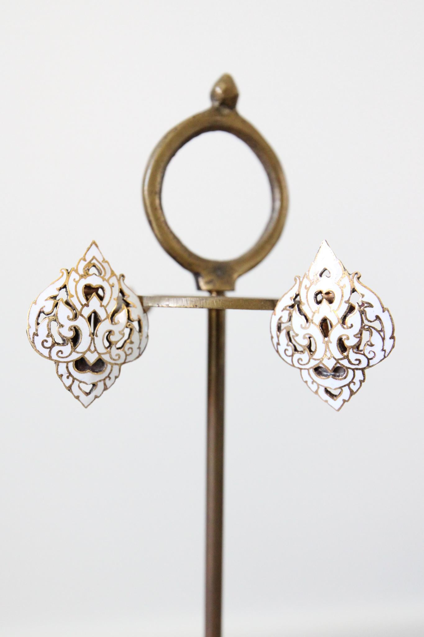 Rendered in white enamel on a gold toned metal base, this pair of 1940's clip on earrings, elegantly decorated in a swirling filigree pattern, are the perfect finishing touch to any outfit.

 

Measurements of the Earrings

Length:  1.4 