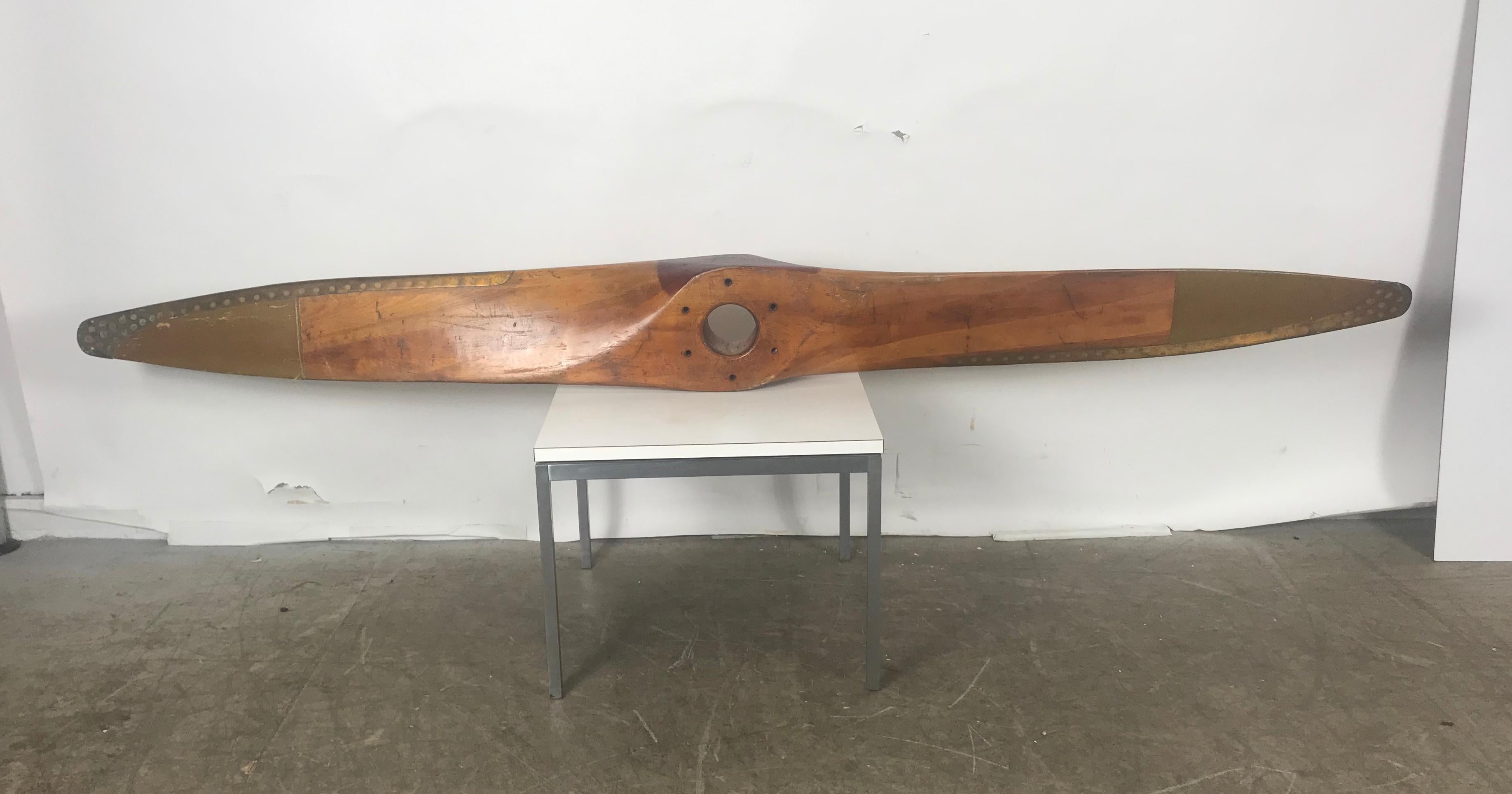 A beautiful wooden airplane propeller manufactured by Fahlin, Columbia Mo., circa 1940s. Salvaged from Curtis Wright, this eye-catching piece is made of high quality wood in a beautiful warm color tones woods and brass strips to the sides, red