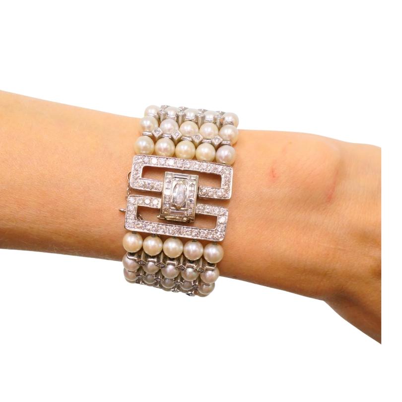 An exquisite vintage bracelet from the 1950s, crafted in 14k white gold and featuring five rows of cultured pearls, arranged in a structured honeycomb pattern. Alternating between the pearls are square diamond spacers. The clasp is detailed with