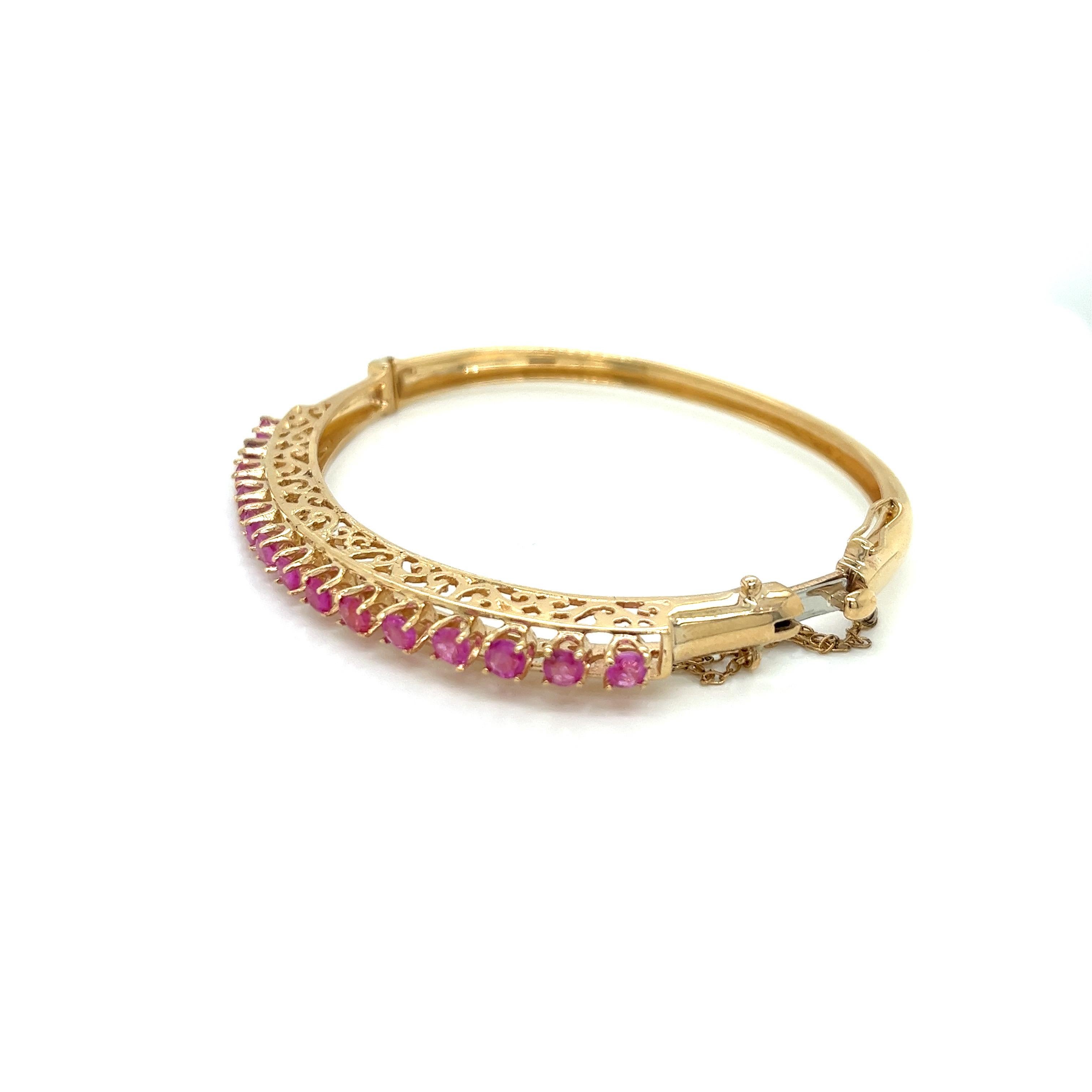 Vintage 1950's 14K Yellow Gold Ruby Bangle Bracelet - The bangle is set with 14 round light color rubies weighing approximately 2.50ct total weight. The measurement of the rubies across the top is 2.25