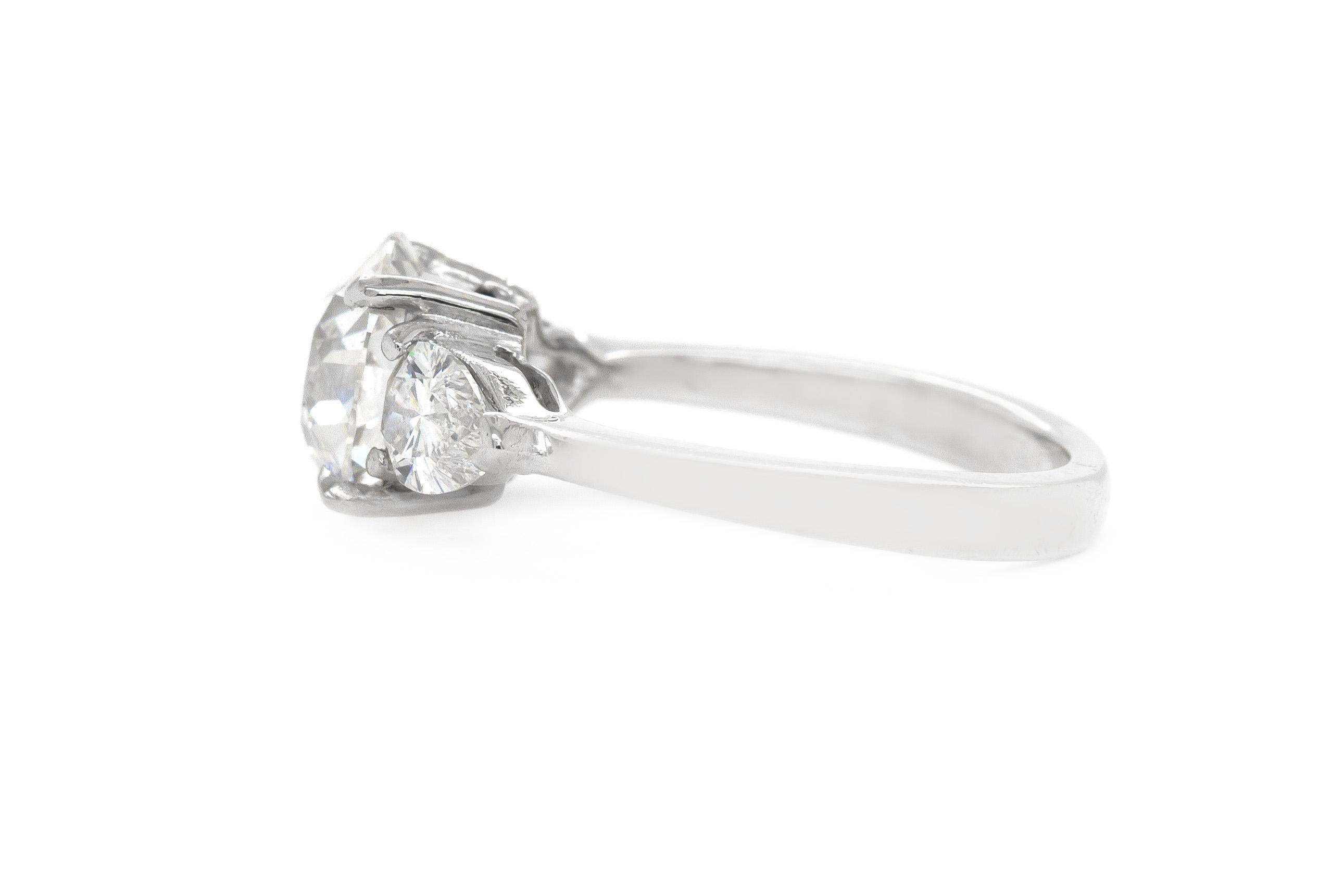 Finamente elaborada en platino con un Diamante talla Vieja Europea certificado por el GIA en el centro que pesa 1,64 quilates, color G, claridad SI2, GIA #5201453975.
El anillo presenta dos Diamantes laterales en forma de Pera que pesan en total