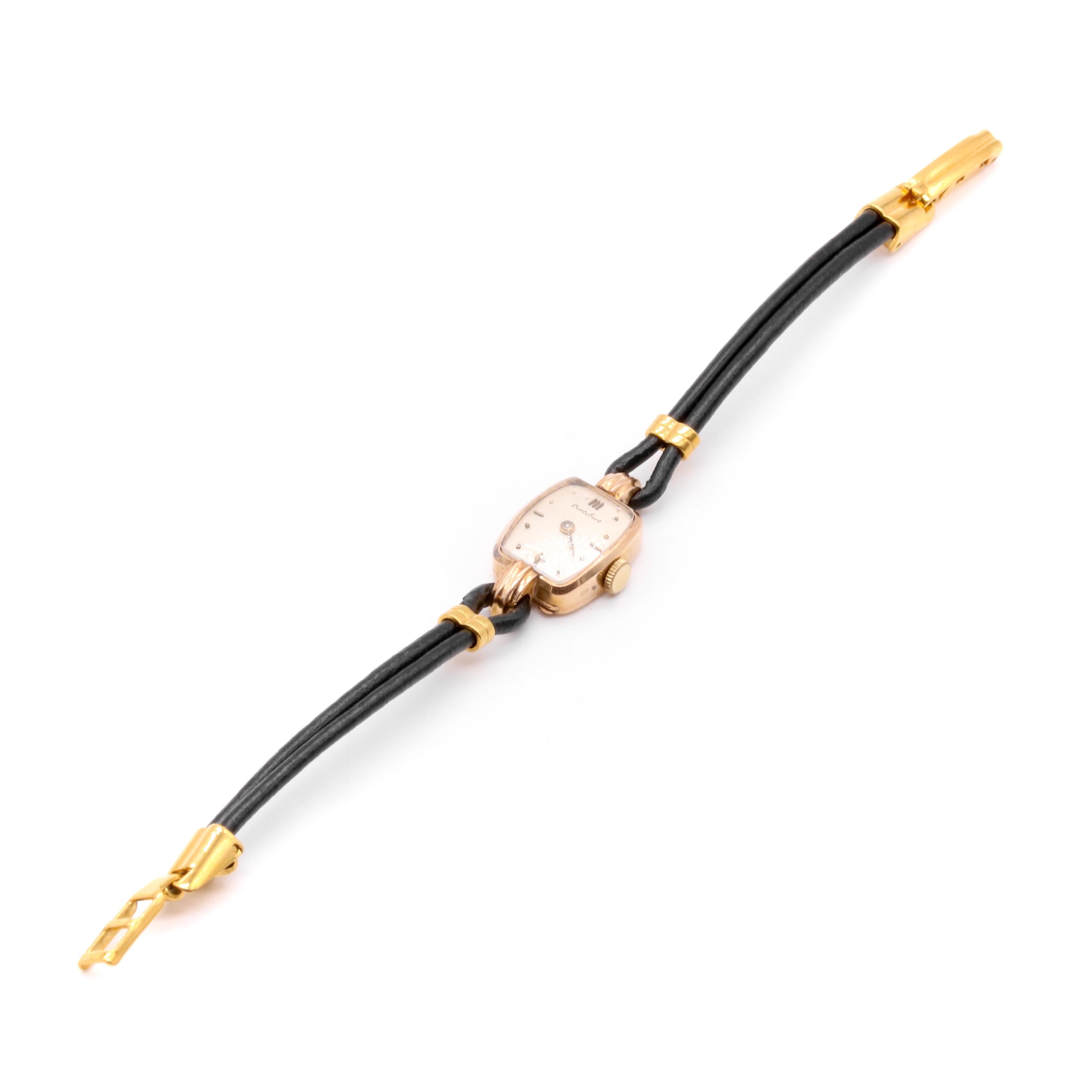 Reloj vintage de oro amarillo, con esfera color champán, caja de oro amarillo de 18 quilates y correa de piel negra con apliques de metal amarillo. 

Este elegante reloj de cóctel vintage tiene forma de rombo y está fabricado en oro amarillo. El oro