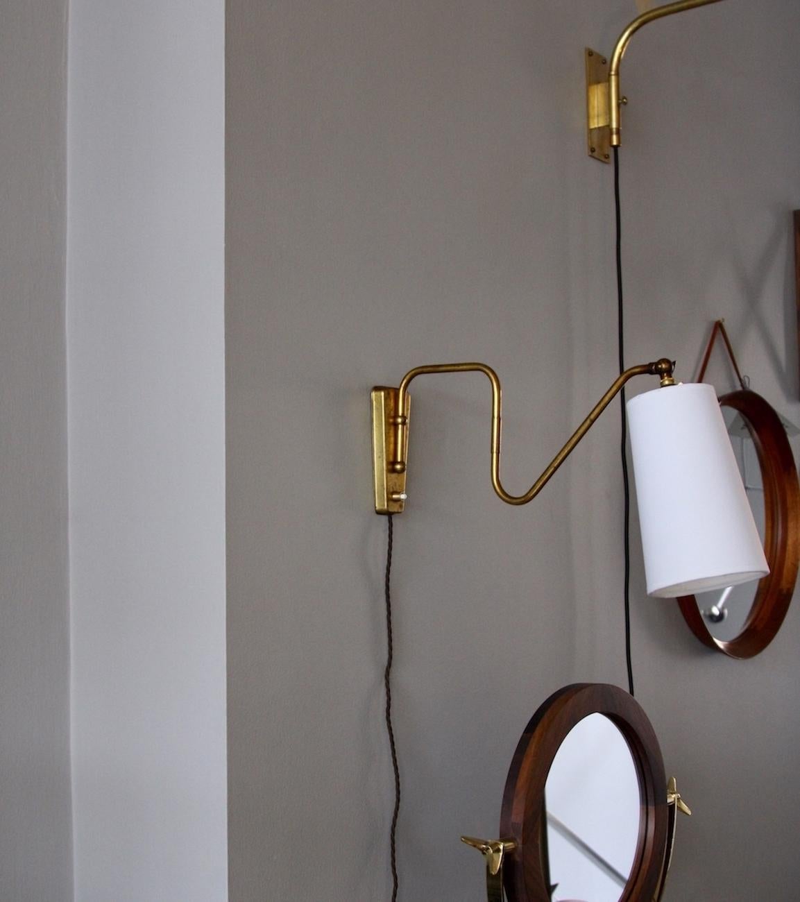 A petite wall light in polished brass, designed and made in Denmark circa 1950.
The arm of the light can move around a 180 degree angle. The pivot point is on the downwards rod parallel to the wall bracket. Loosening the wing-nut behind the bulb