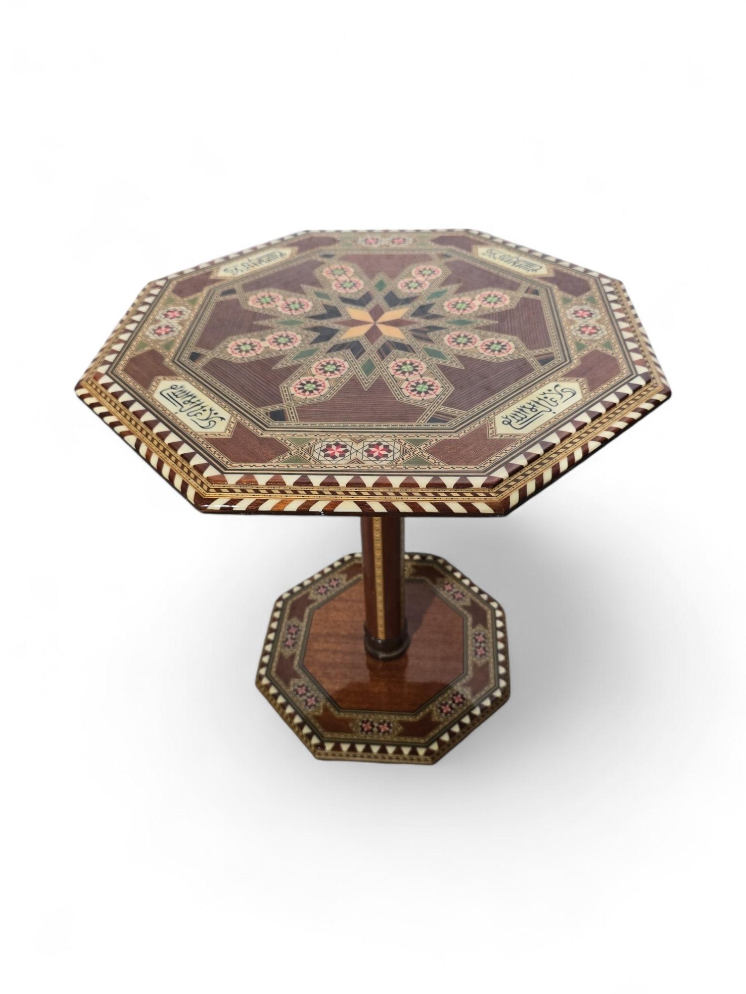 Add a touch of exotic elegance to your home with this exquisite Arabesque inlaid table from the 1950s. Handcrafted in Granada, Spain, this small table showcases intricate marquetry, Arabic calligraphy, and the beauty of exotic woods, reflecting the