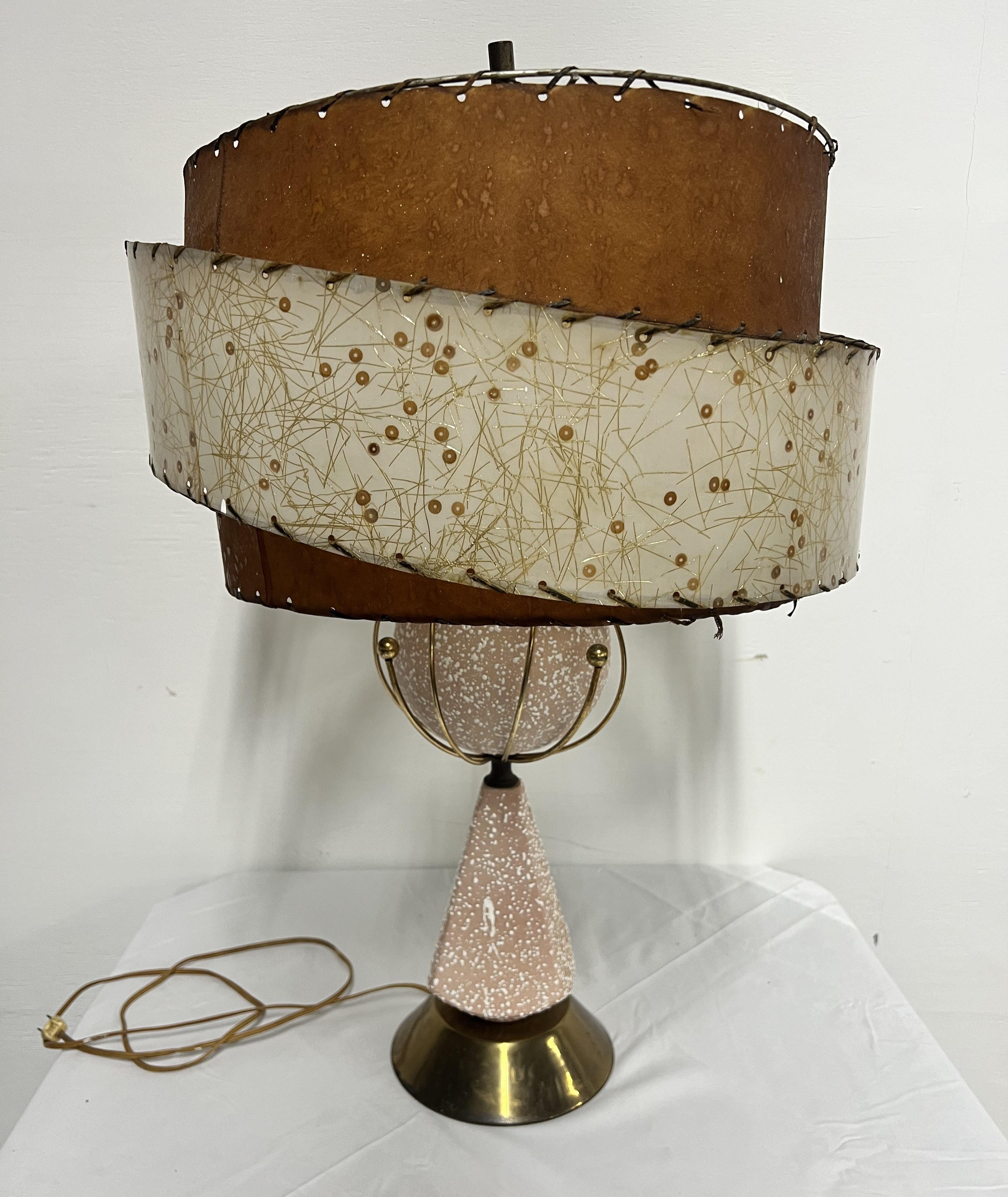Mid Cenury Modern 1950s Atomic Pink Table Lamp
Ceramic with original Fiberglass shade 
Pink base has raised paint splatters throughout and has gold metal accents
Vintage condition shows sign of wear and tear
