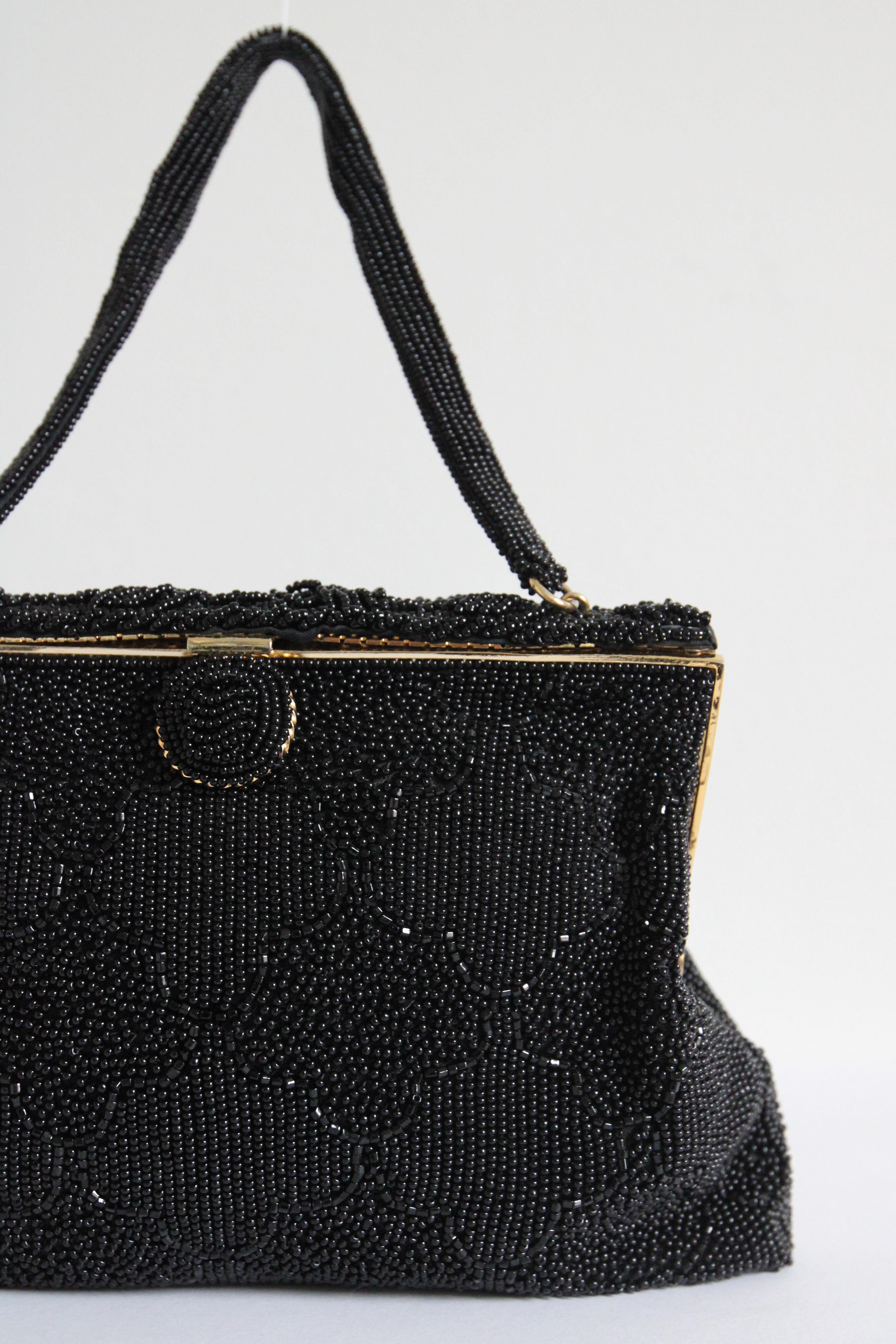 This intricately made 1950's evening bag, embellished with black glass seed beads and small bugle beads, is the perfect piece for your accessory collection.

The elegant gold toned metal frame of the bag, is decorated with braided and twisted