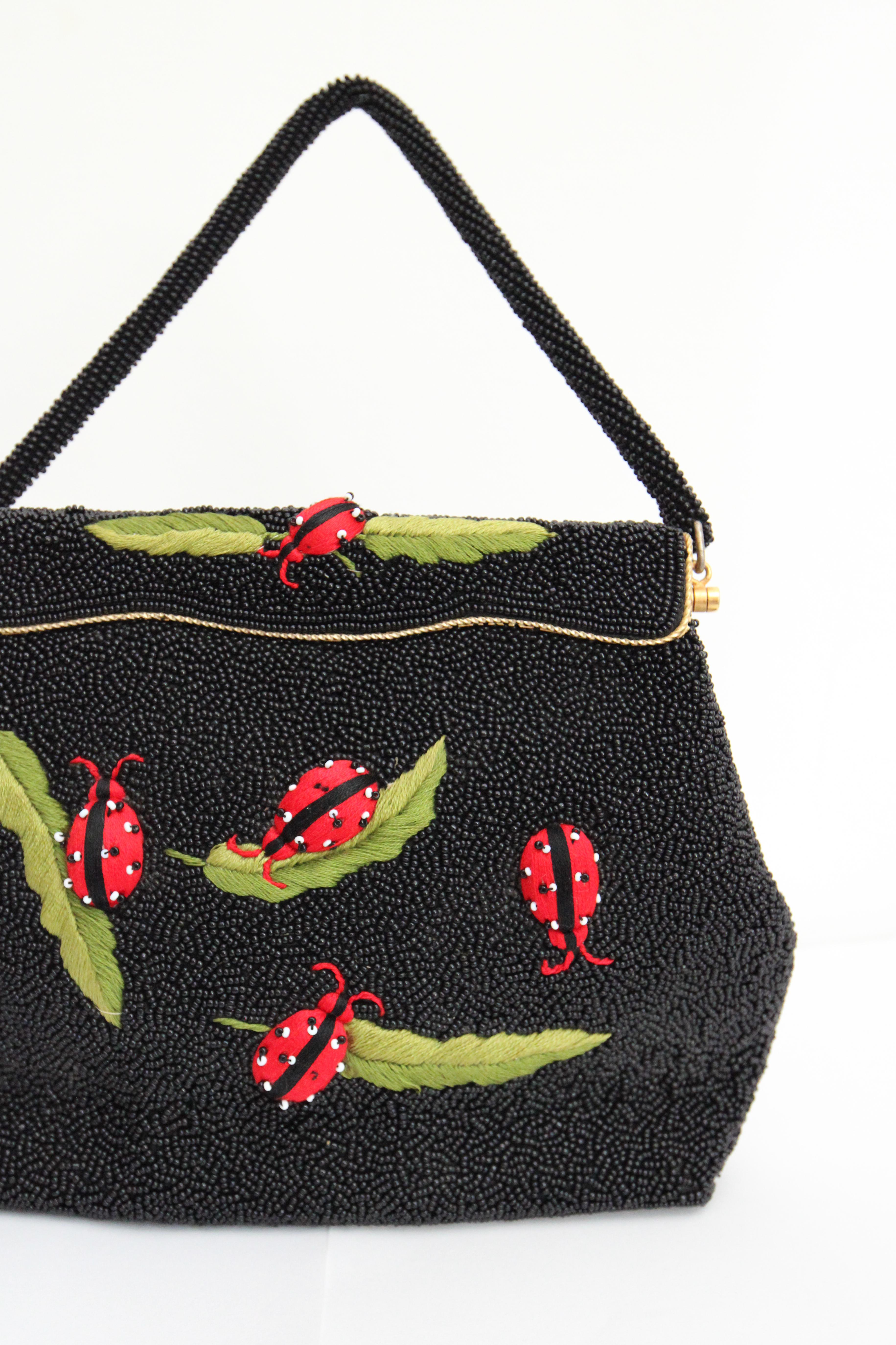 A true beauty to behold, this original late 1950's beaded handbag, rendered in an undulating pattern of black rocaille beads, accented by raised embroidered ladybugs finished with delicate beadwork and embroidered leaf designs, is the perfect piece