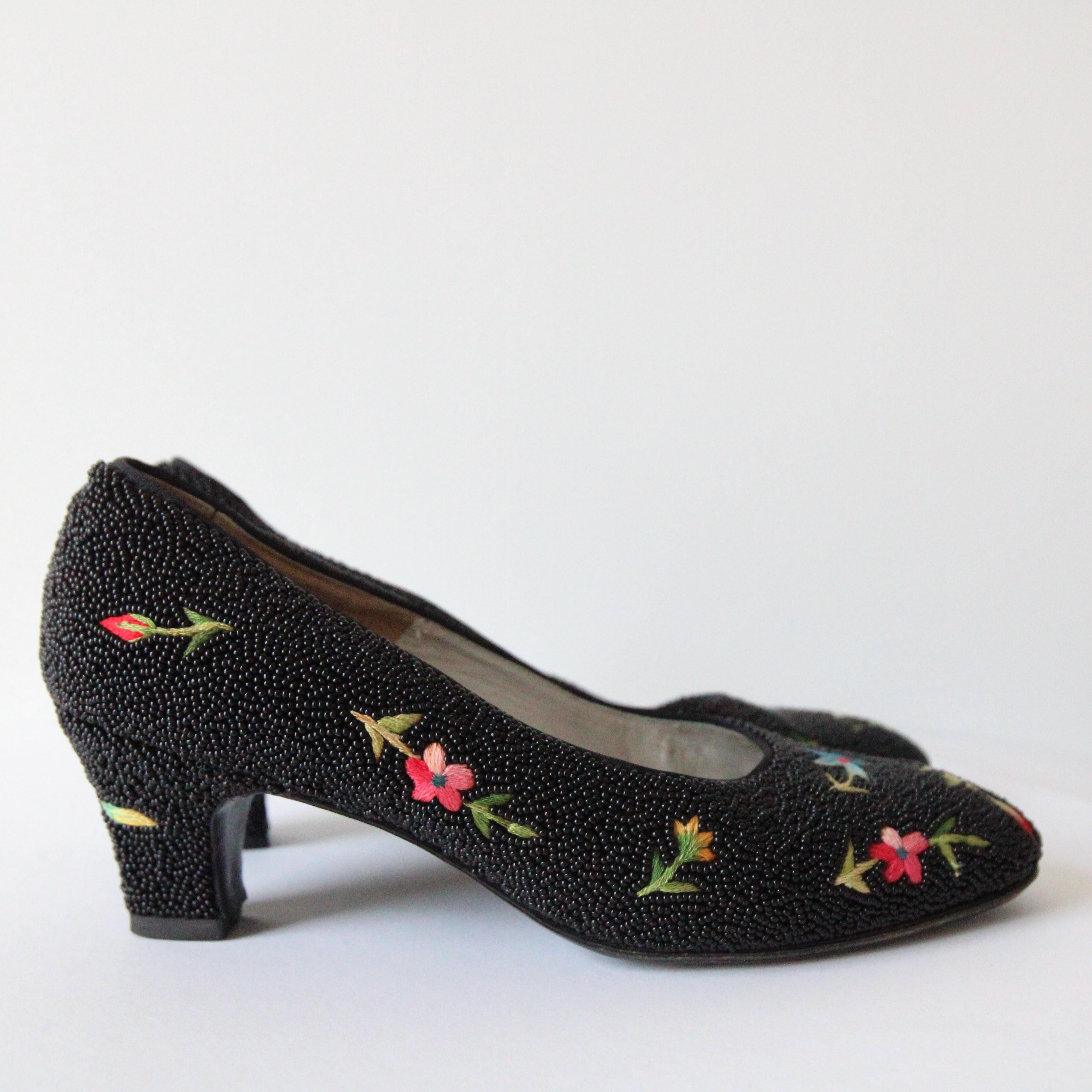 The most beautiful little pair of shoes you could ever hope to set eyes upon.

The delicate shoe encloses the front of the foot in a rounded toe, showcasing the most delightful silk embroidered flowers along the main body, surrounded by black glass