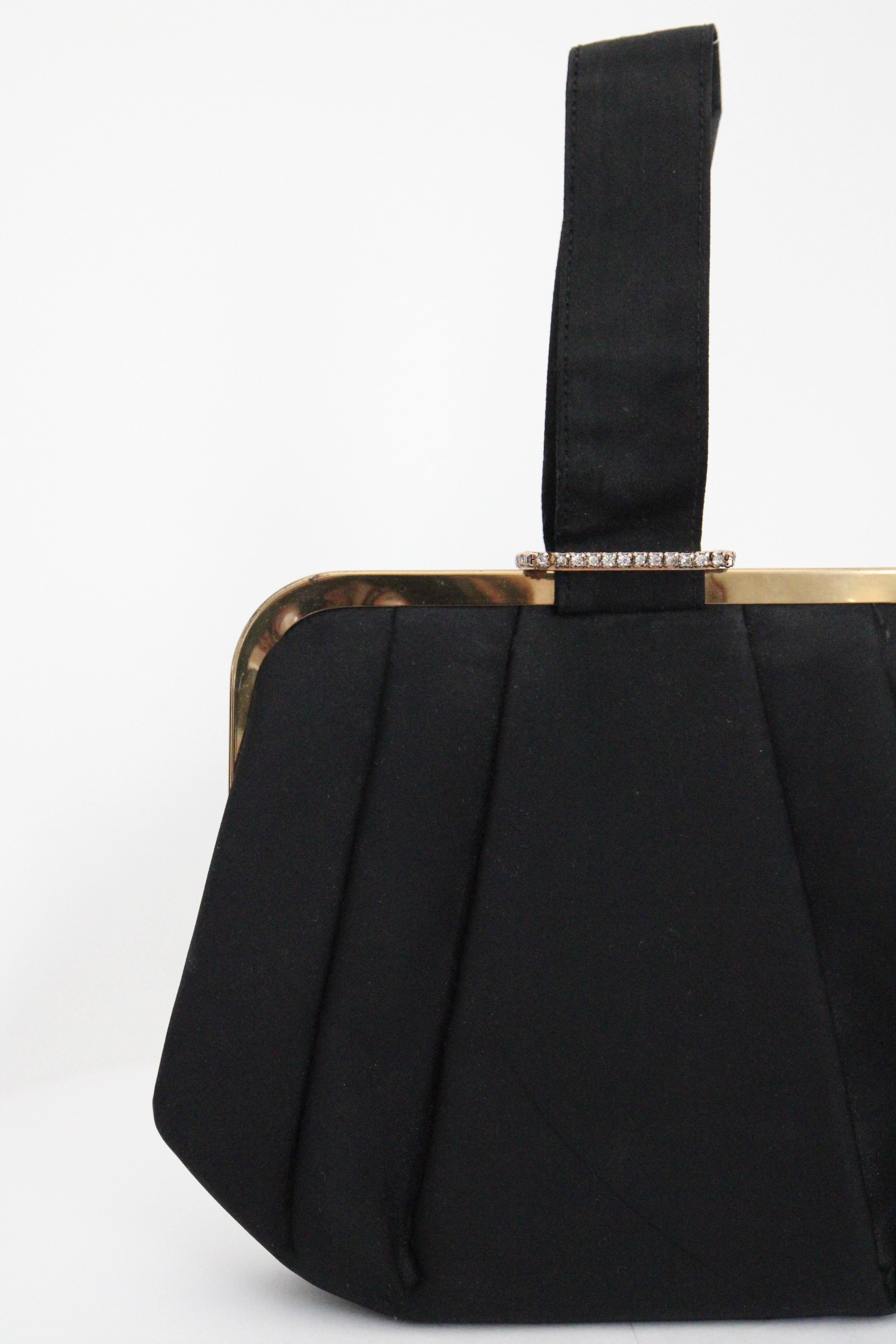 Rendered in the most sumptuous black satin, accented by silver claw set rhinestones and gold toned metal hardware, this original 1950's handbag , is the perfect accessory for any vintage lover. 

The elegant rounded sides of the bag, set off the