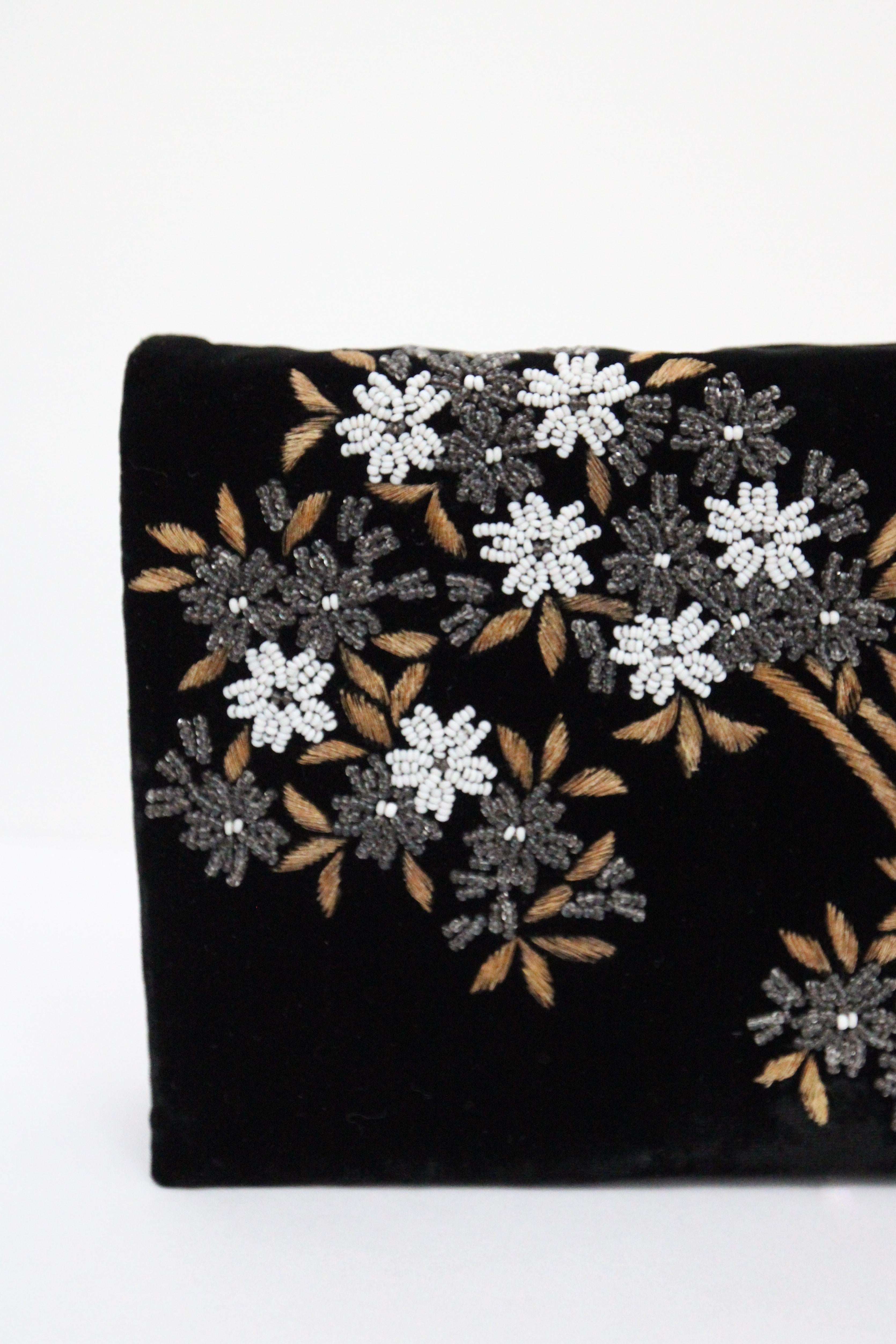 A true beauty to behold, this original 1950's black velvet bag, embellished with silver and white glass beaded blossoms, surrounded by gold thread leaf design embroidery, is the perfect piece to add to your vintage collection. The rectangular shape