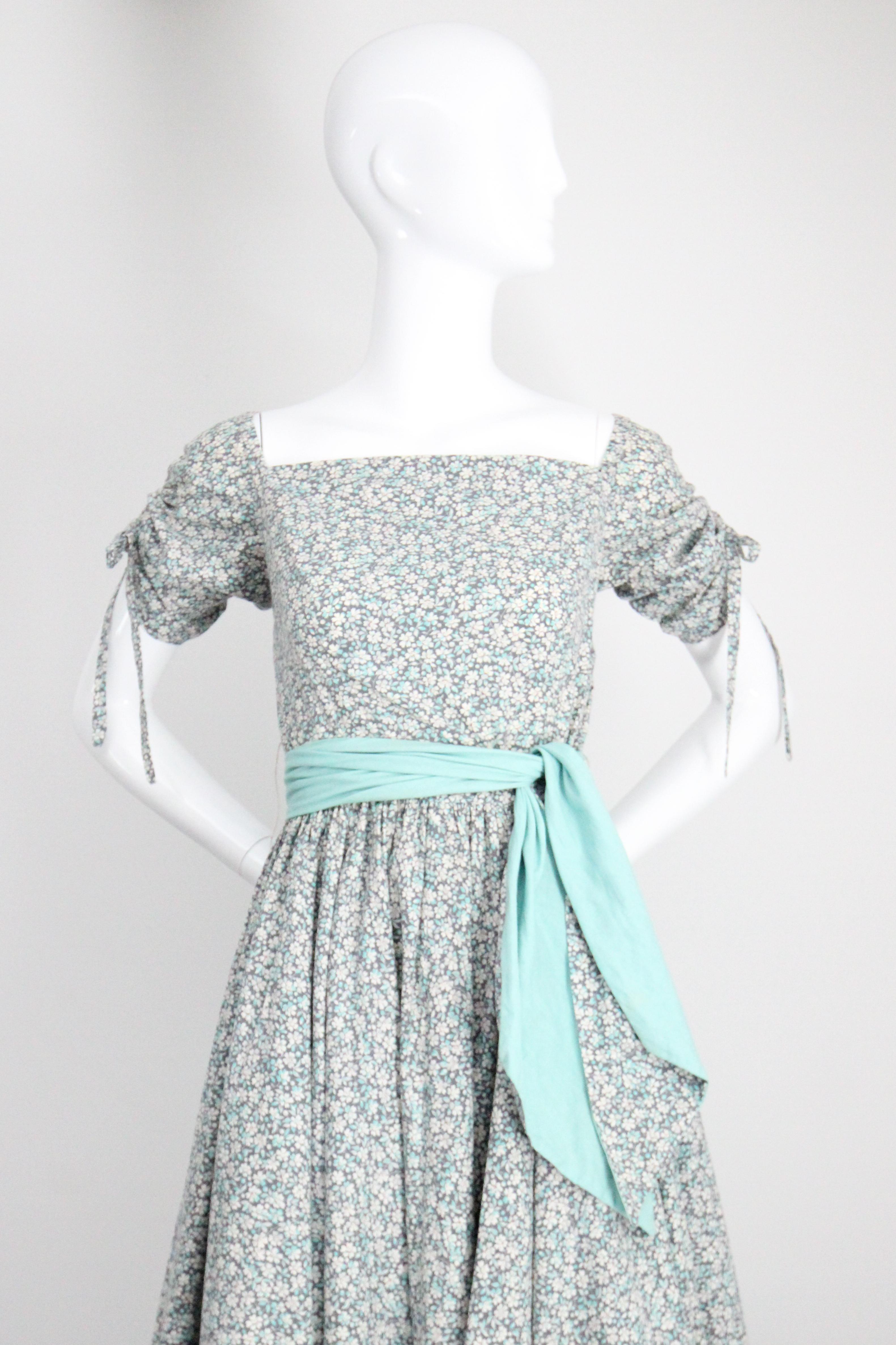 Este original vestido circular de algodón de los años 50, con un impresionante estampado floral en tonos azules, grises y blancos, es la prenda perfecta para dar la bienvenida al buen tiempo.

El escote recto del vestido realza las costuras