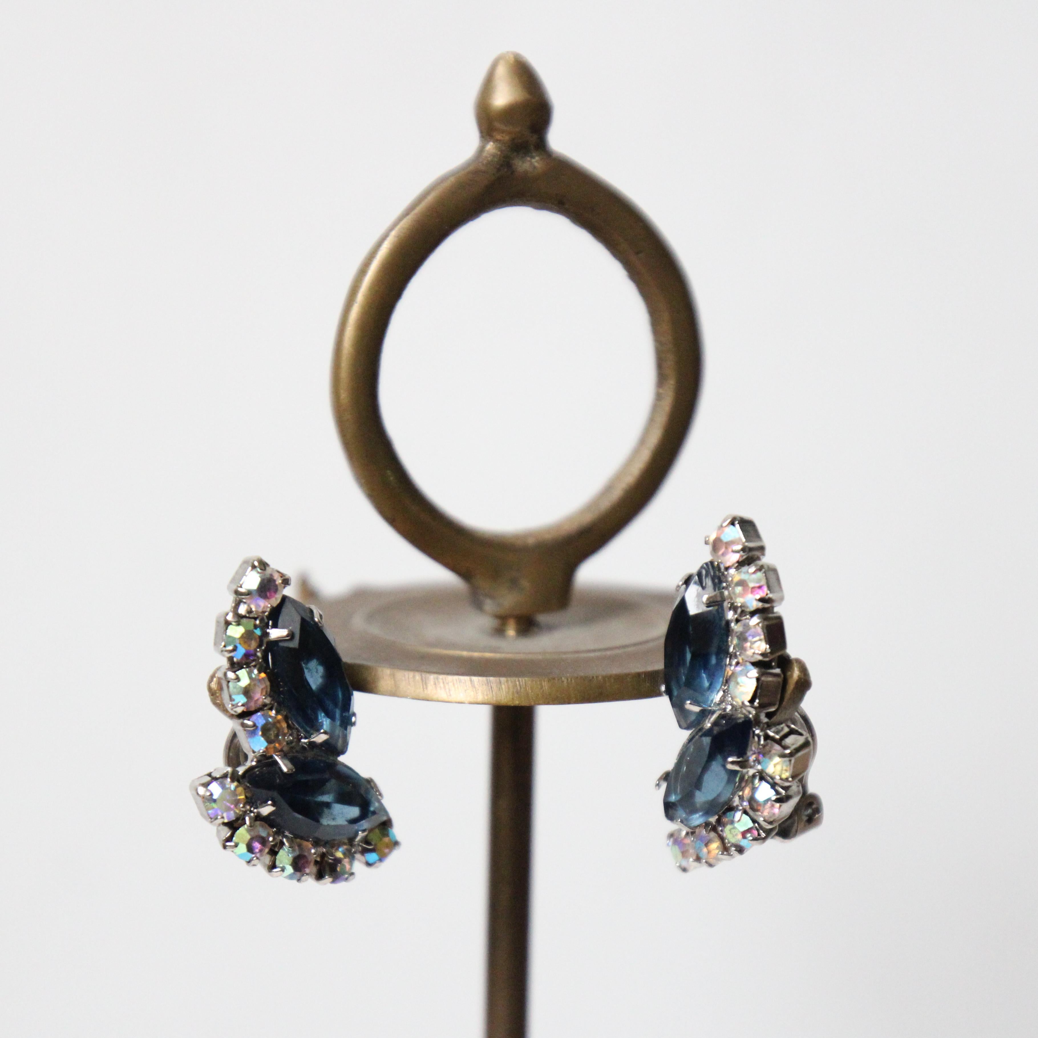 This sparkling pair of 1950's clip on earrings, made up of two larger leaf cut rhinestones in a deep shade of blue, framed by borders of iridescent claw set rhinestones, in a climbing leaf design, are the perfect finishing touch to any