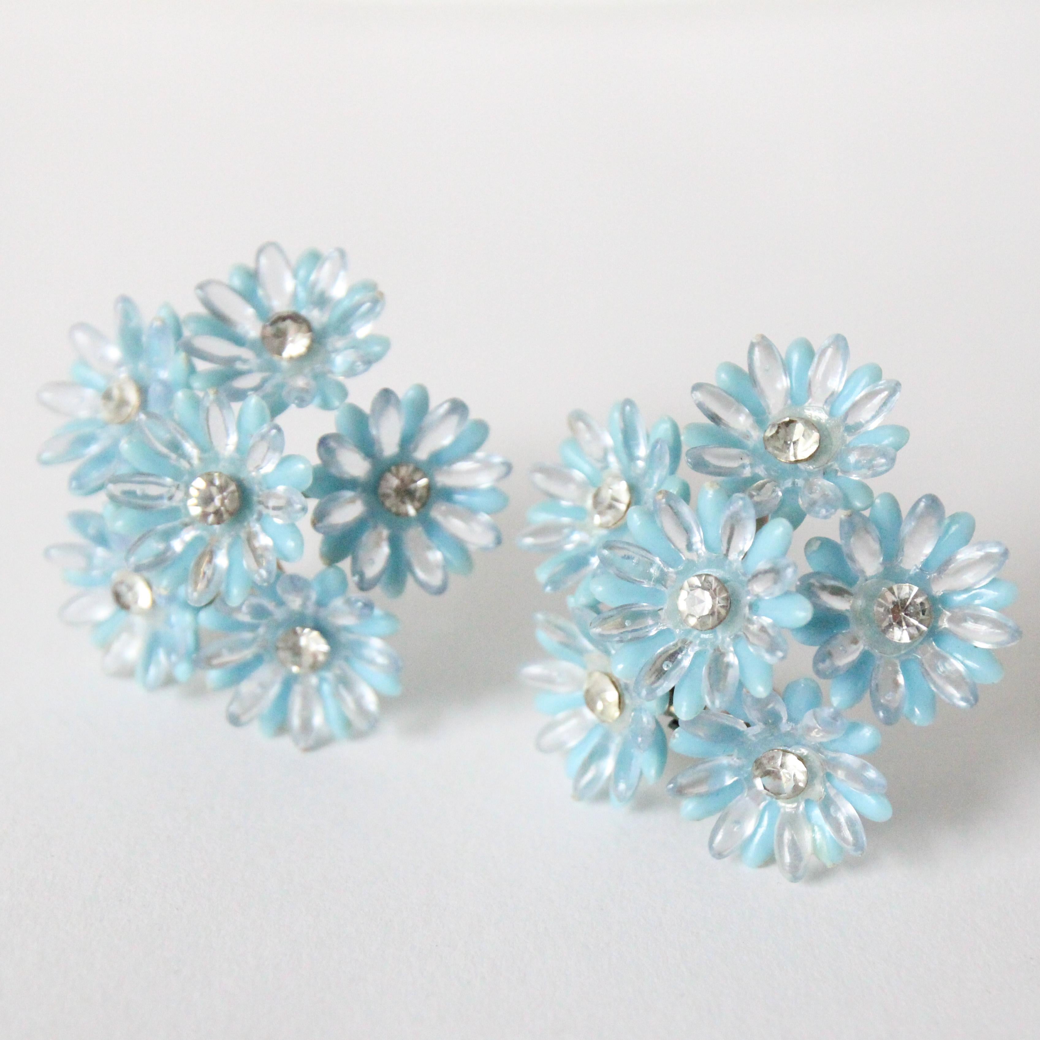 This beautiful pair of statement 1950's floral clip on earrings, with silver rhinestone centres framed by two layers of petals in blue and clear plastic, are the perfect statement piece for your wardrobe. 

Length: 1.7 inches
 
Width: 1.7