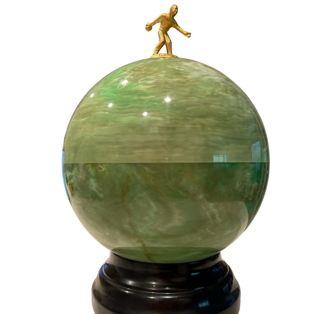 Excellent condition! Green marble plastic mold in shape of bowling ball with gold plated bowler figurine finial; it opens to mini bar set; 6 shot glasses with revolving silver tray sitting on top of decanter that holds liquor; bottom of ball could