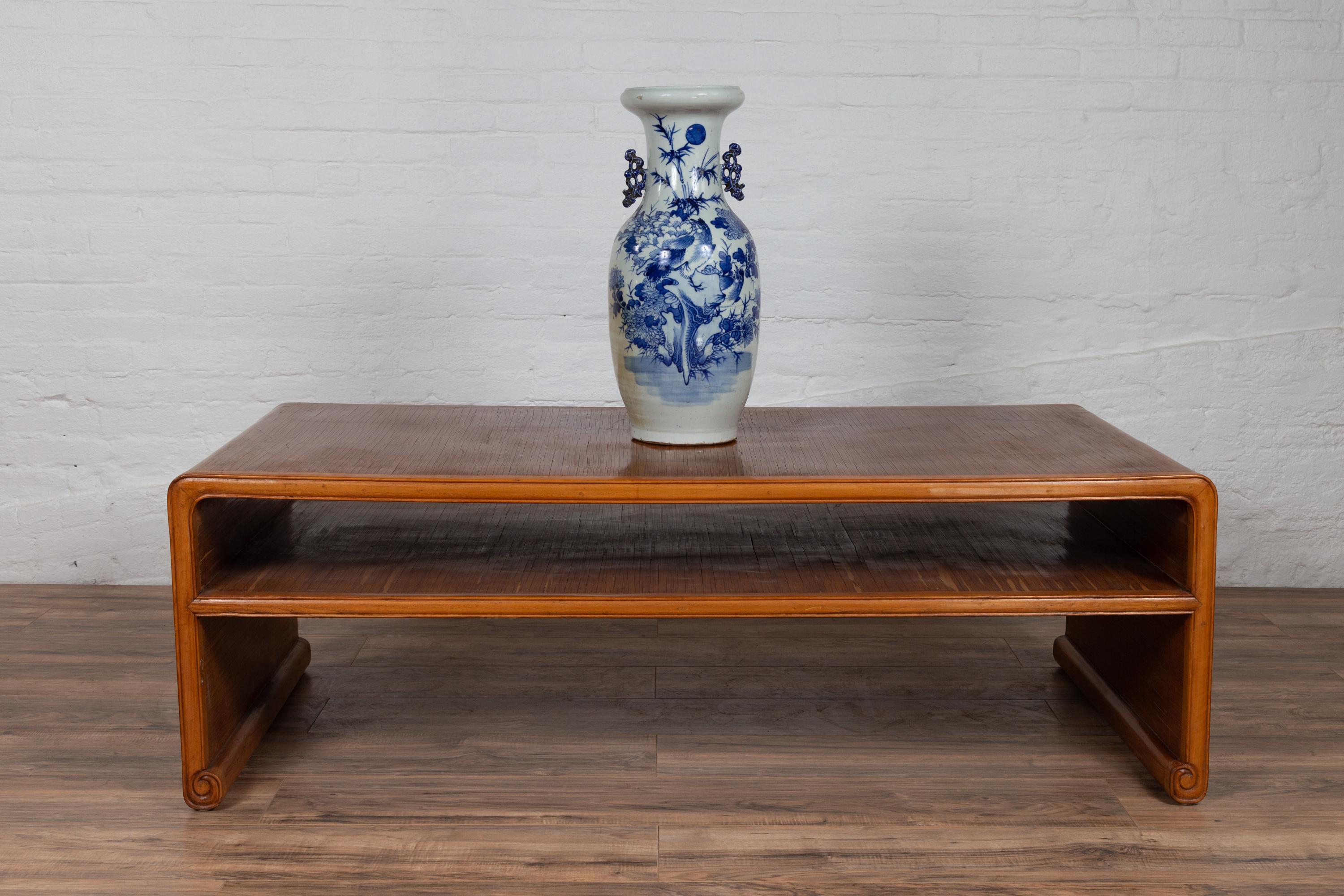 A Burmese vintage waterfall table from the mid-20th century, with opium mat top and scrolling feet. Born in Burma during the midcentury period, this elegant waterfall table features a rectangular opium mat top resting on solid legs, accented with