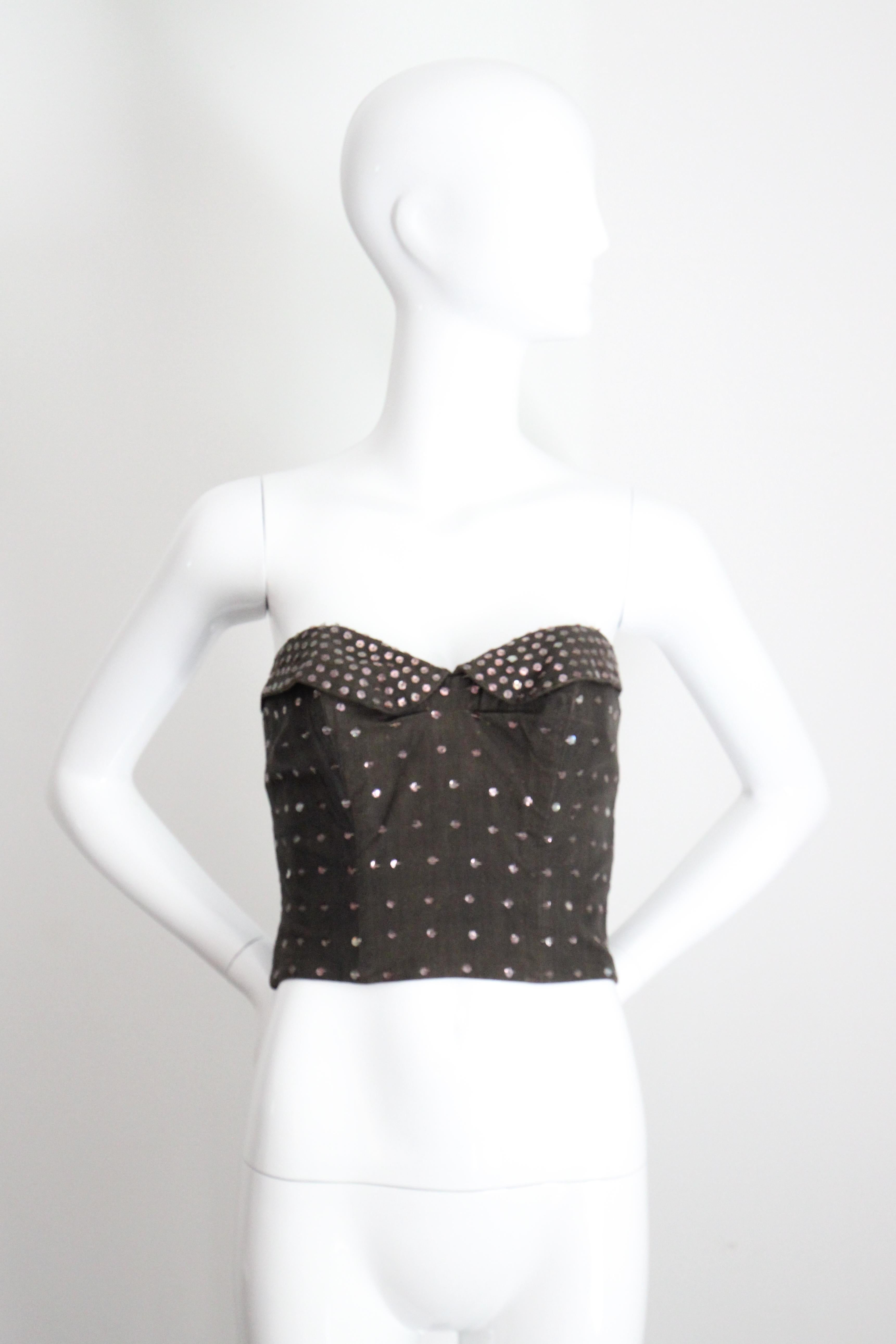 Rendered in the softest of charcoal black cottons, the original 1950s vintage bustier, embellished with a pattern of sewn pink sequins,  is the perfect piece to add a touch of sparkle to your wardrobe.

The sweetheart cut of the neckline is accented