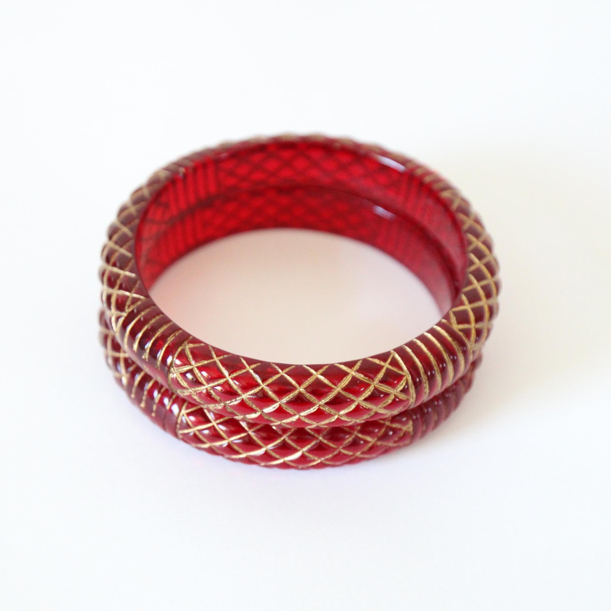 This intricately carved pair of 1950's cherry red lucite bangles, in a crosshatched and linear pattern accented by gold paint, are the perfect set to add to your jewellery collection.  ( sold as a pair )

Measurements of the Bangle

External