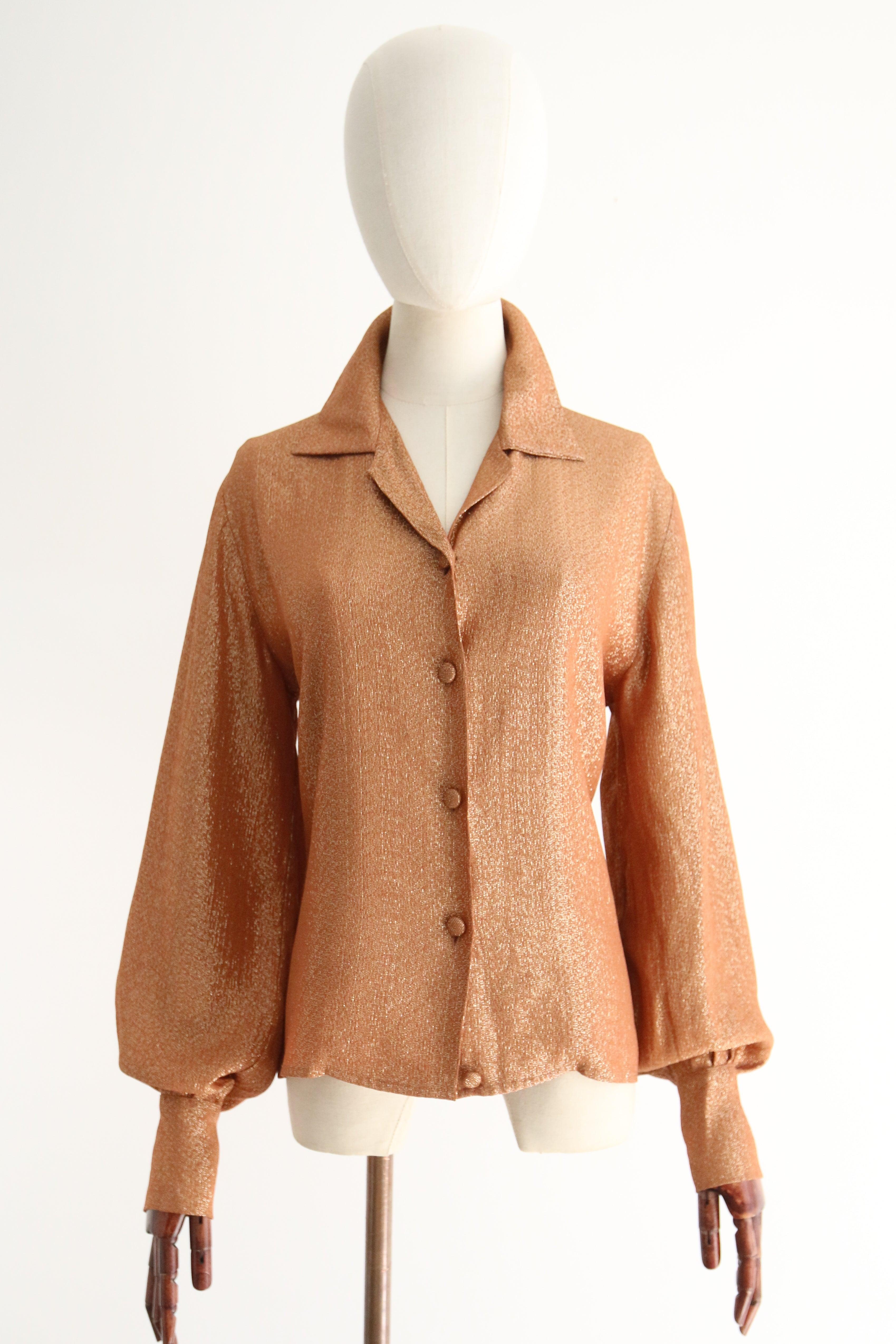 Una pieza brillante para contemplar. Esta original blusa de color coral polvoriento de finales de los años 50, con un acento de hilo de lúrex dorado, es justo la pieza que añadirá un toque de glamour a tu vestuario de diario. 

El escote en forma de