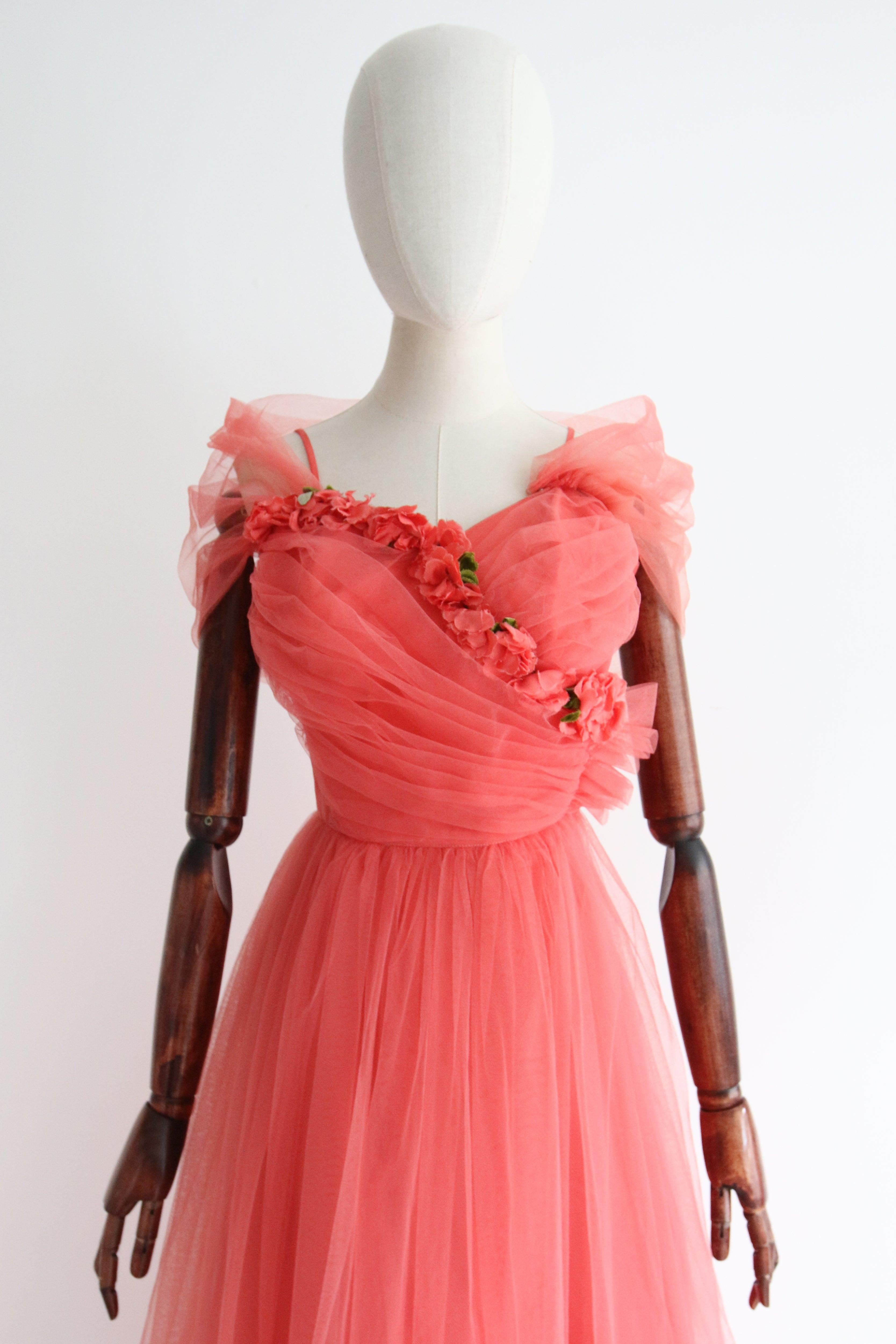 A favourite! This original 1950's tulle dress in the most breathtaking shade of coral tulle, embellished with trailing silk velvet and rayon corsage flowers, is a truly breathtaking piece to add to your vintage collection.   

The sweetheart